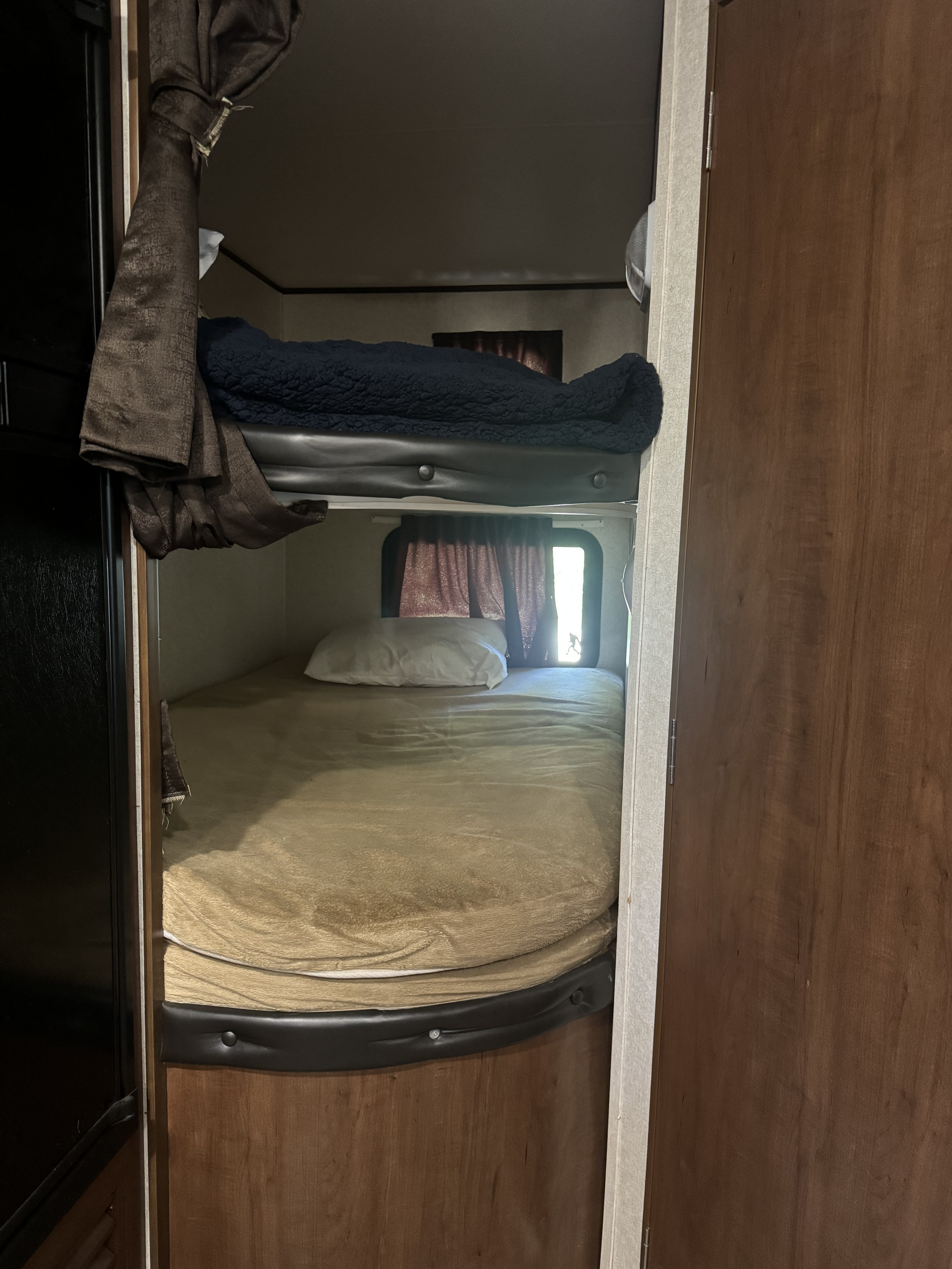 Cozy RV rental features bunk beds, with soft blankets and a pillow. Natural light fills the bottom bunk from a window.. Jayco Jay Flight SLX Baja Edition 2017