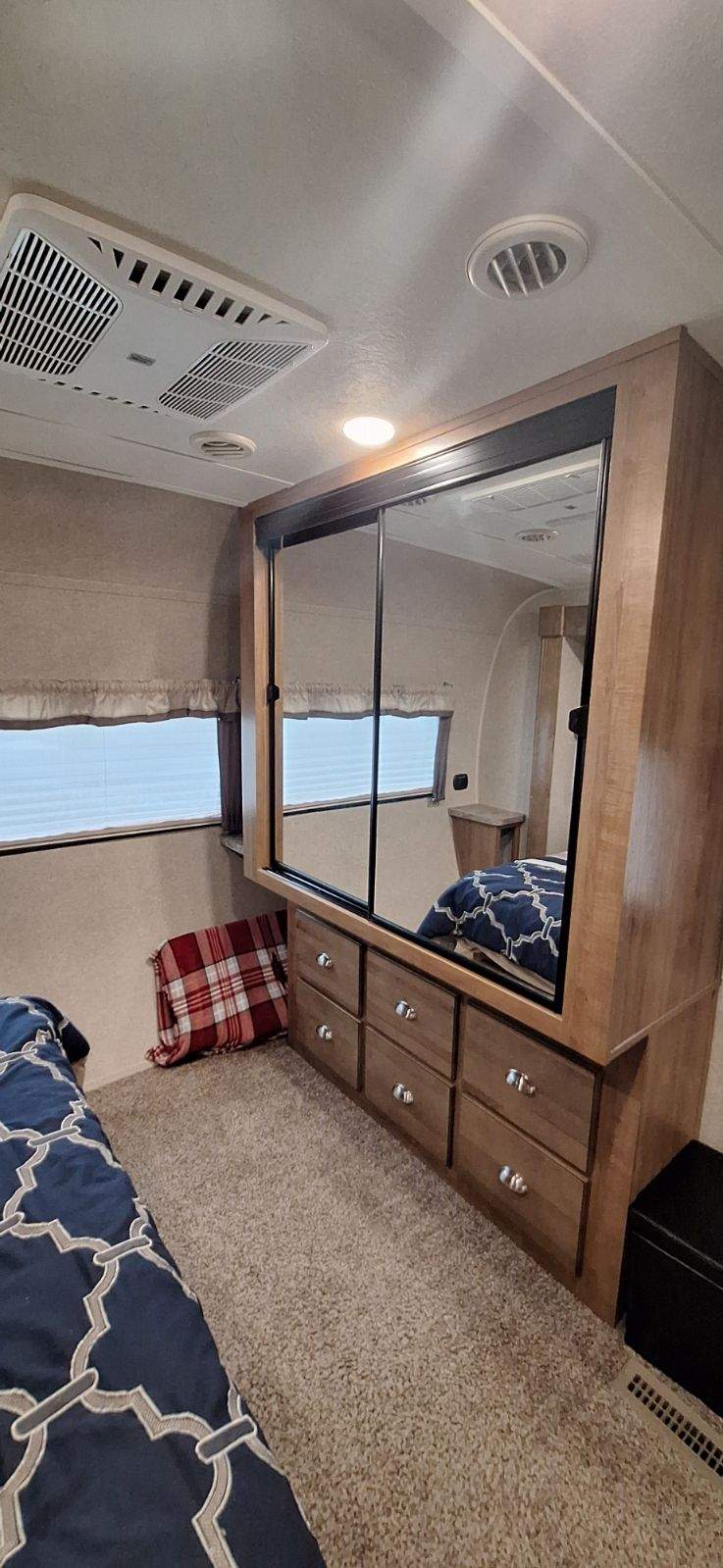 This RV rental bedroom features a mirrored closet/dresser, comfortable bed, windows, and ceiling-mounted AC.. Flagstaff Classic Super Lite 2018