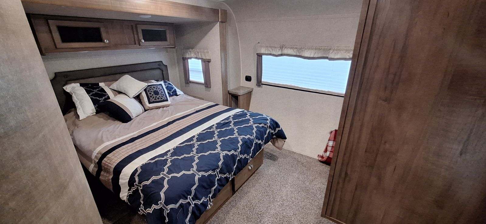 RV rental bedroom: a cozy space featuring a comfortable bed with striped bedding, pillows, cabinets, and windows.. Flagstaff Classic Super Lite 2018