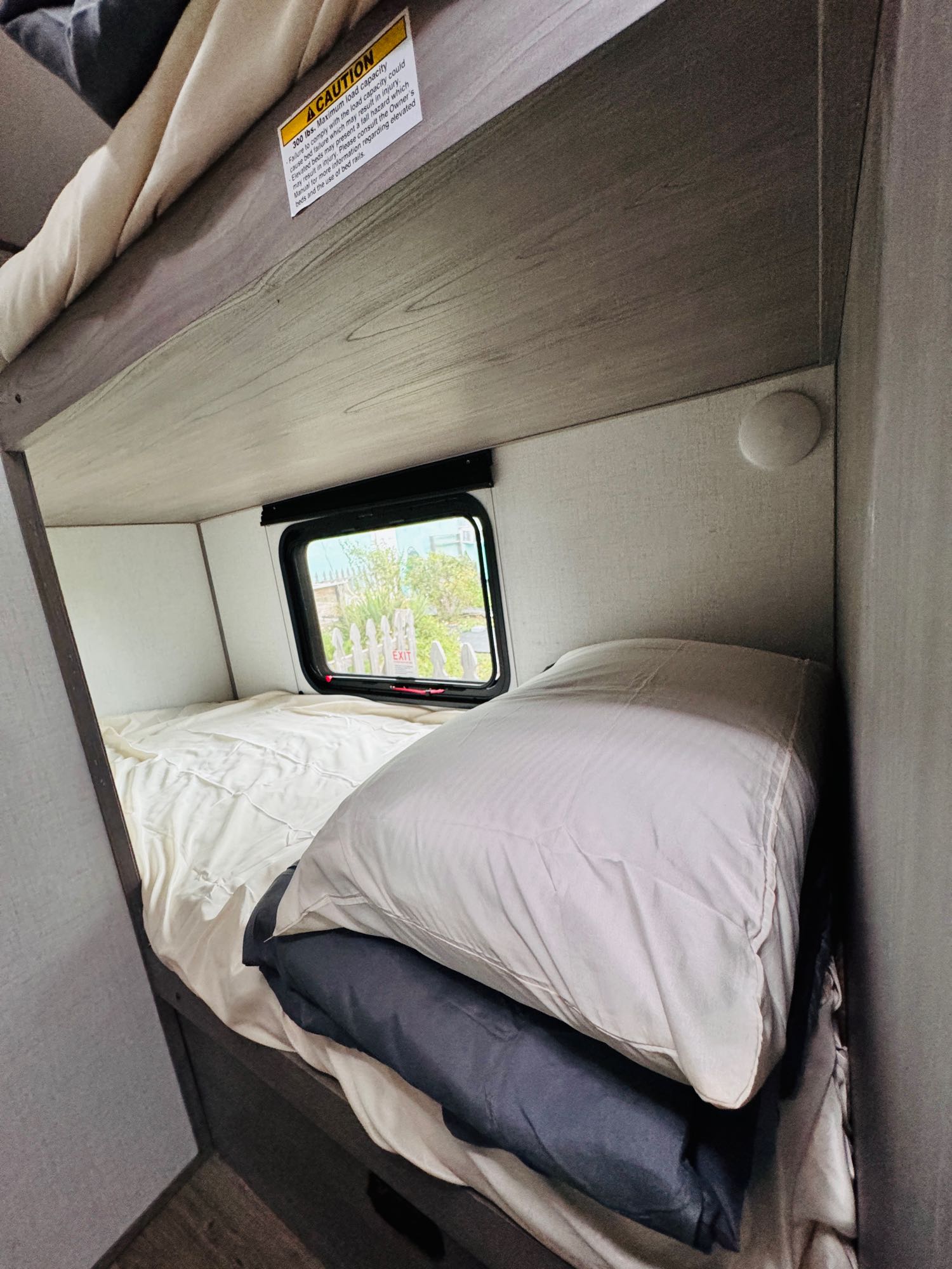 RV rental bunk bed setup with clean bedding, a window to the outside, and an important 300 lb capacity warning.. Dutchmen 4ydtcmg18r8932632 2024