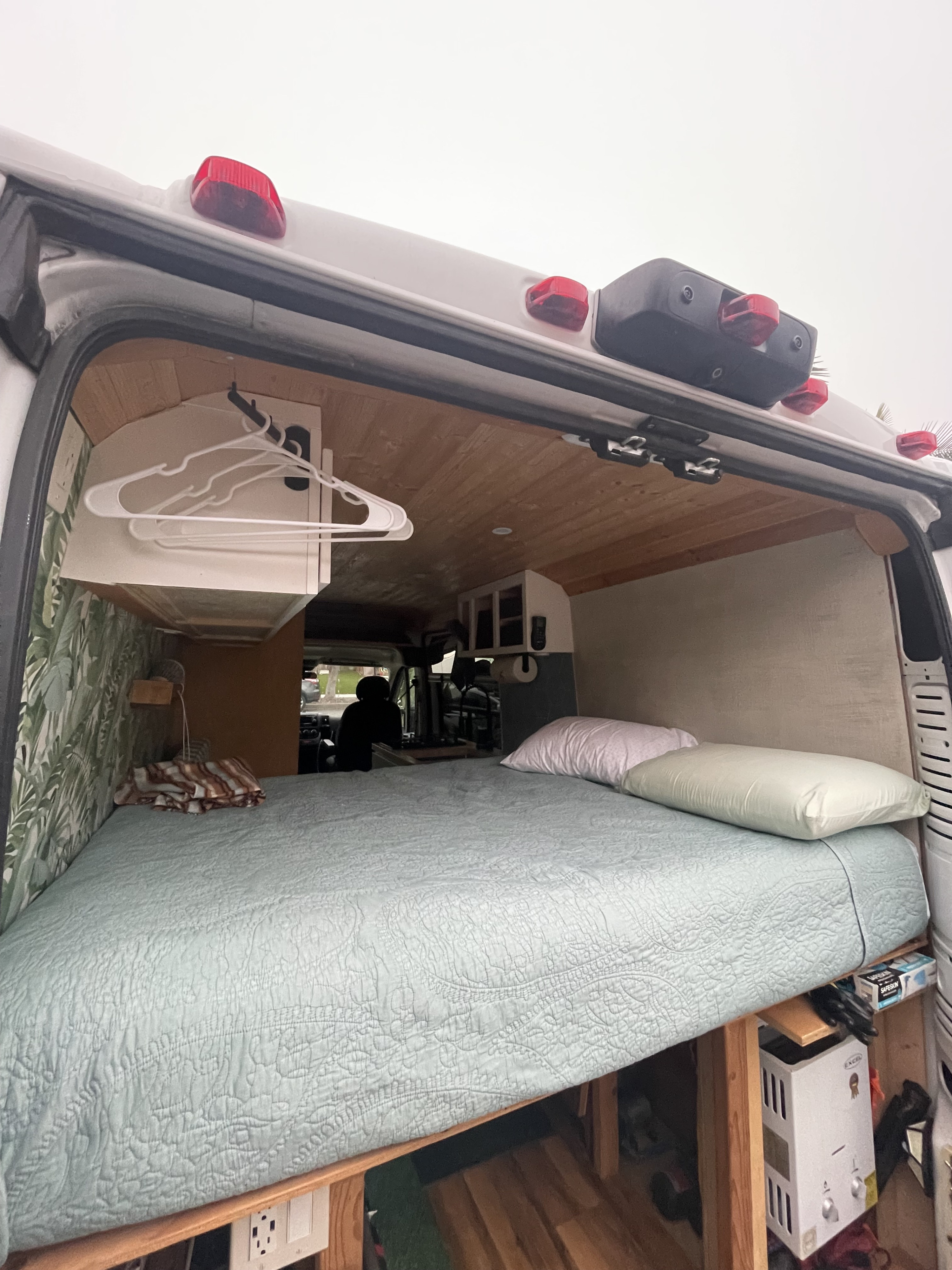 Cozy RV rental interior: large bed, wood ceiling, storage, and visible water heater for comfort.. Dodge Ram ProMaster 2500 eco diesel 2015