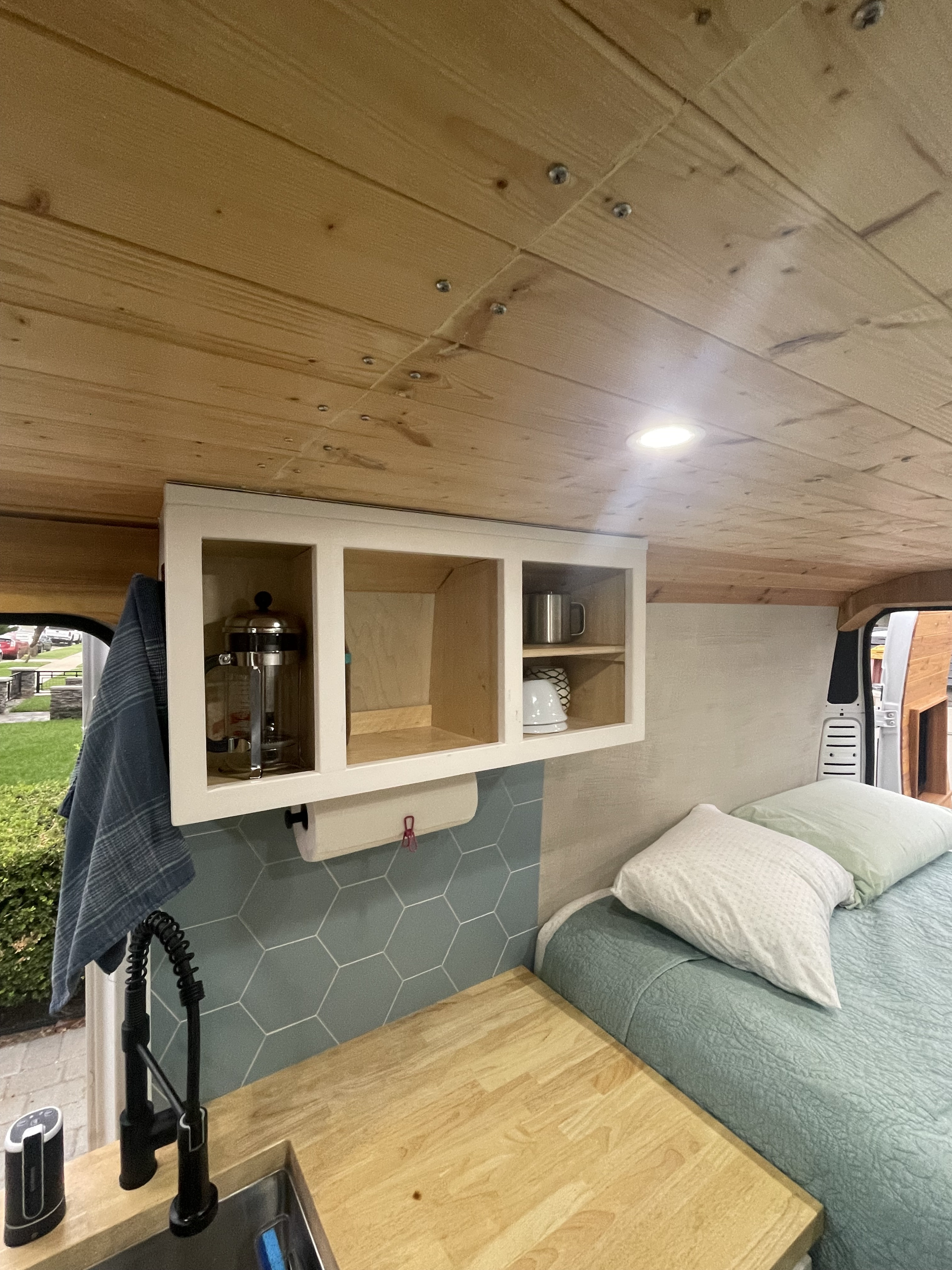 Inside a modern RV rental: custom wood ceiling, kitchen with tiled backsplash, bed, and overhead storage.. Dodge Ram ProMaster 2500 eco diesel 2015