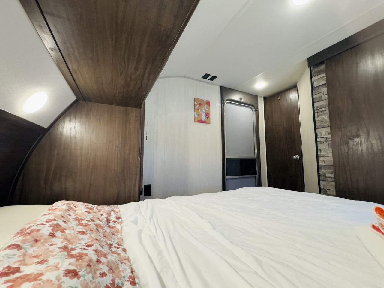 Cozy RV rental bedroom with dark wood trim and white bedding. Perfect compact accommodations for your next travel adventure.. Forest River Cherokee Grey Wolf 2021