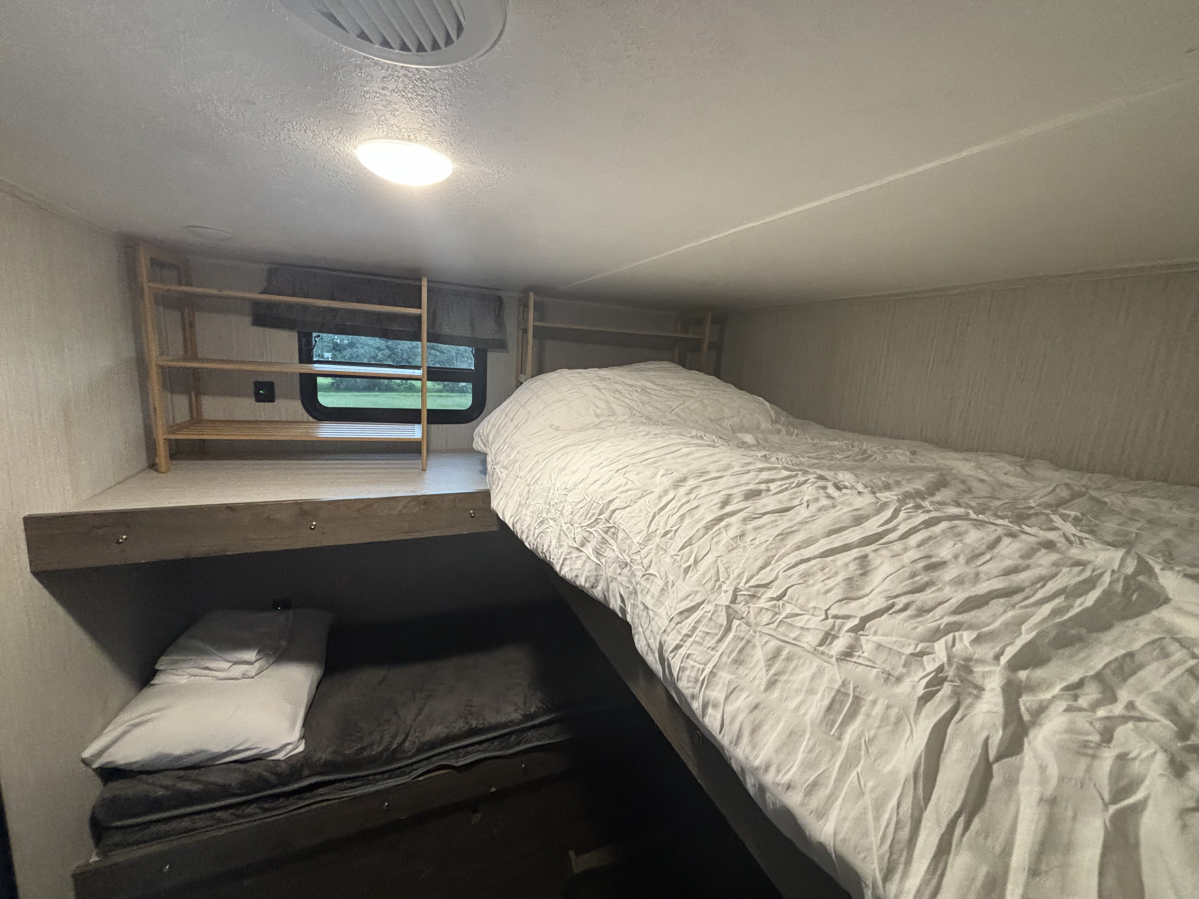 Cozy rv rental bunk beds, with an upper bed and lower bunk, window view, and shelves for storage. Ideal for travel.. Forest River Palomino Puma 2021