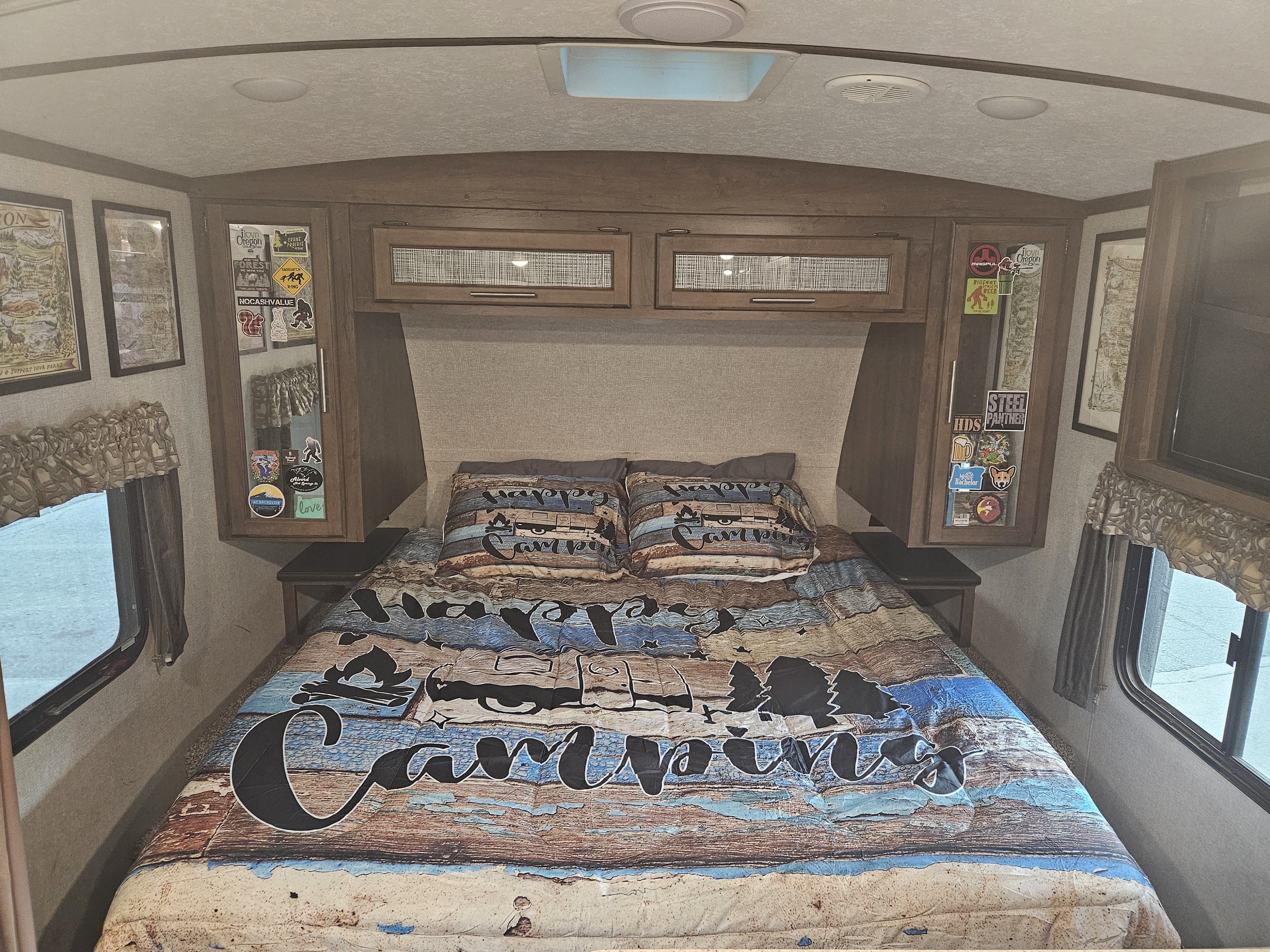 An RV rental bedroom with "Happy Camper" bedding, custom decals, ready for your next road trip.. Keystone RV Cougar 2019