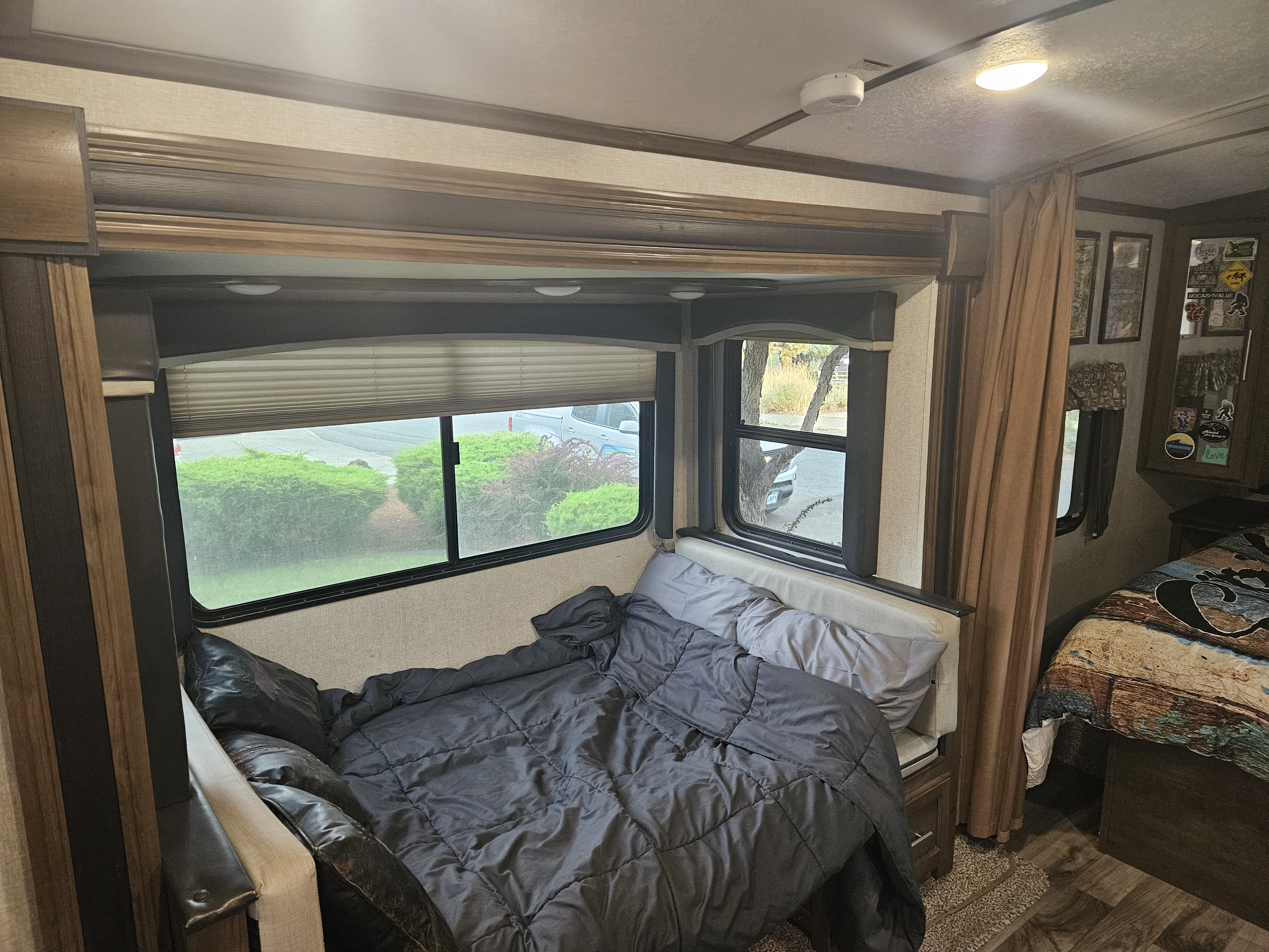 RV rental interior: cozy bedroom with dark bedding & windows, plus a second sleeping area, ideal for mobile living.. Keystone RV Cougar 2019