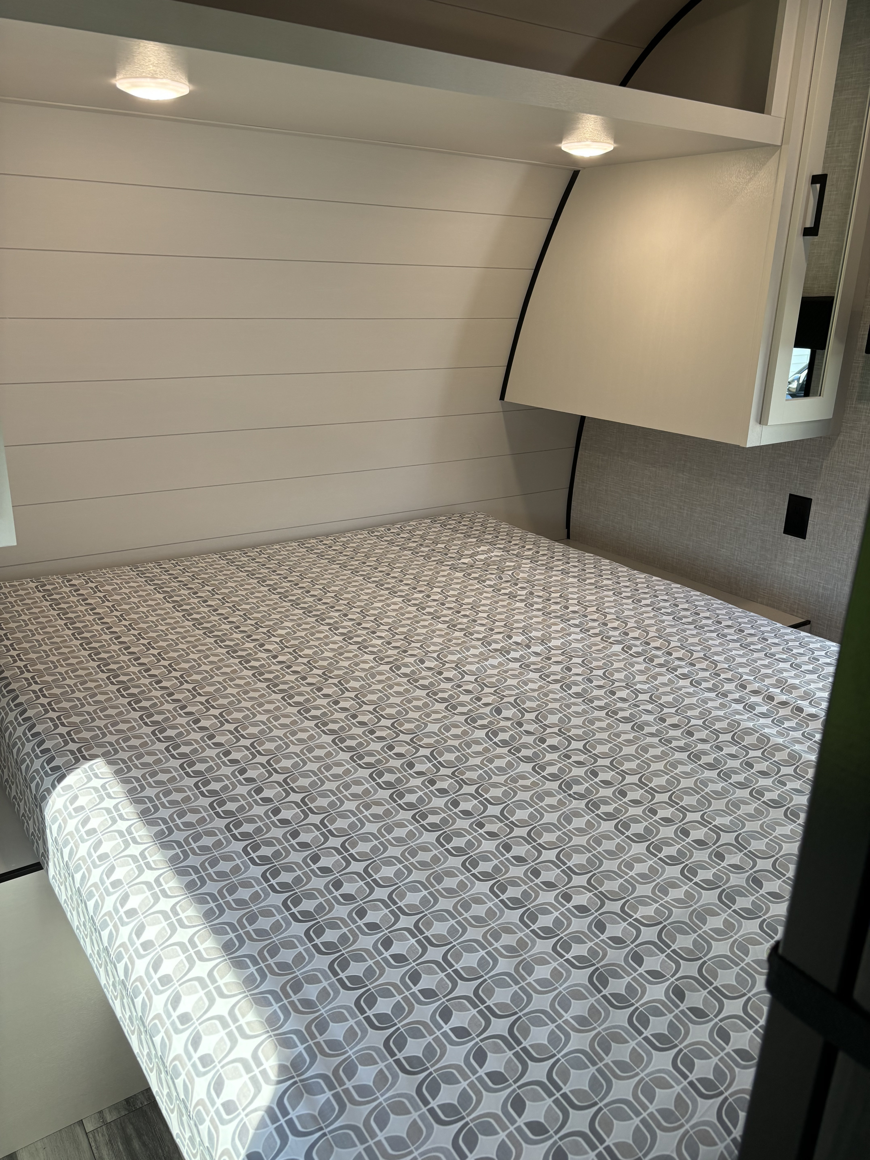 Inside an RV rental: a clean, modern bed with a unique patterned mattress, shiplap walls, and convenient overhead storage.. Jayco Jay Flight SLX 2024