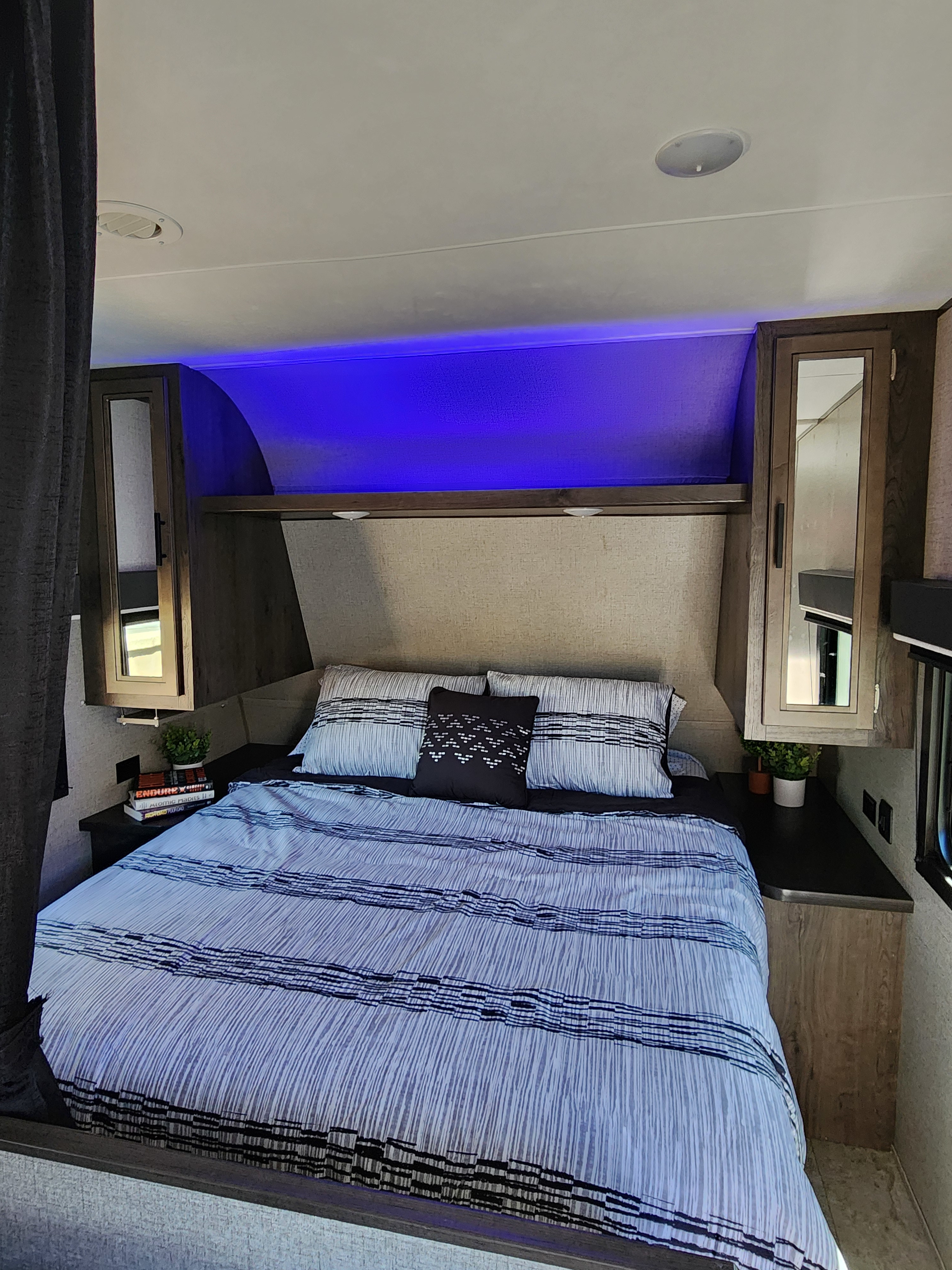 Cozy RV rental bedroom with blue accent lighting, striped bedding, and convenient overhead storage.. Jayco Jay Flight SLX Rocky Mountain Edition 2020