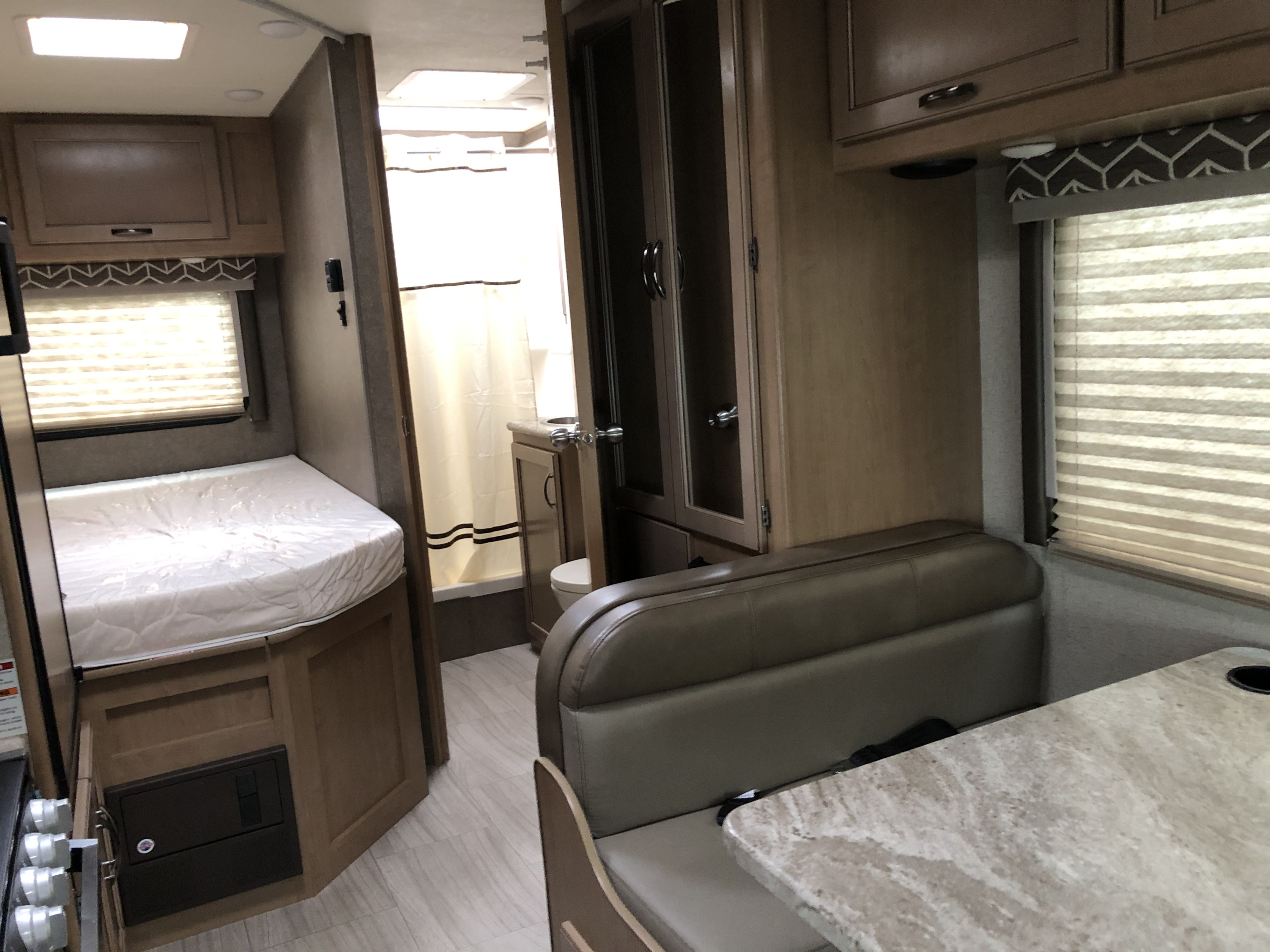 Inside this RV rental: a compact living space with bed, bathroom, and dining booth. Ideal for comfortable road trips.. Thor Daybreak 2020