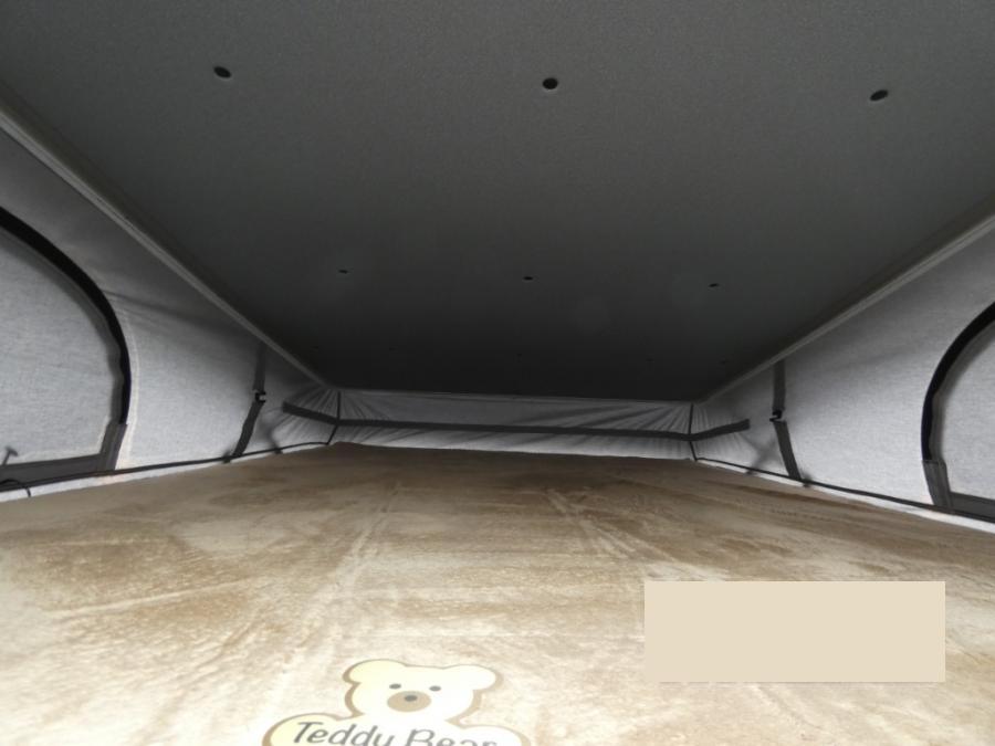 Explore in comfort with this RV rental! View inside a cozy pop-top tent with soft bed, fabric walls & low ceiling.. Entegra Coach Ethos 2024