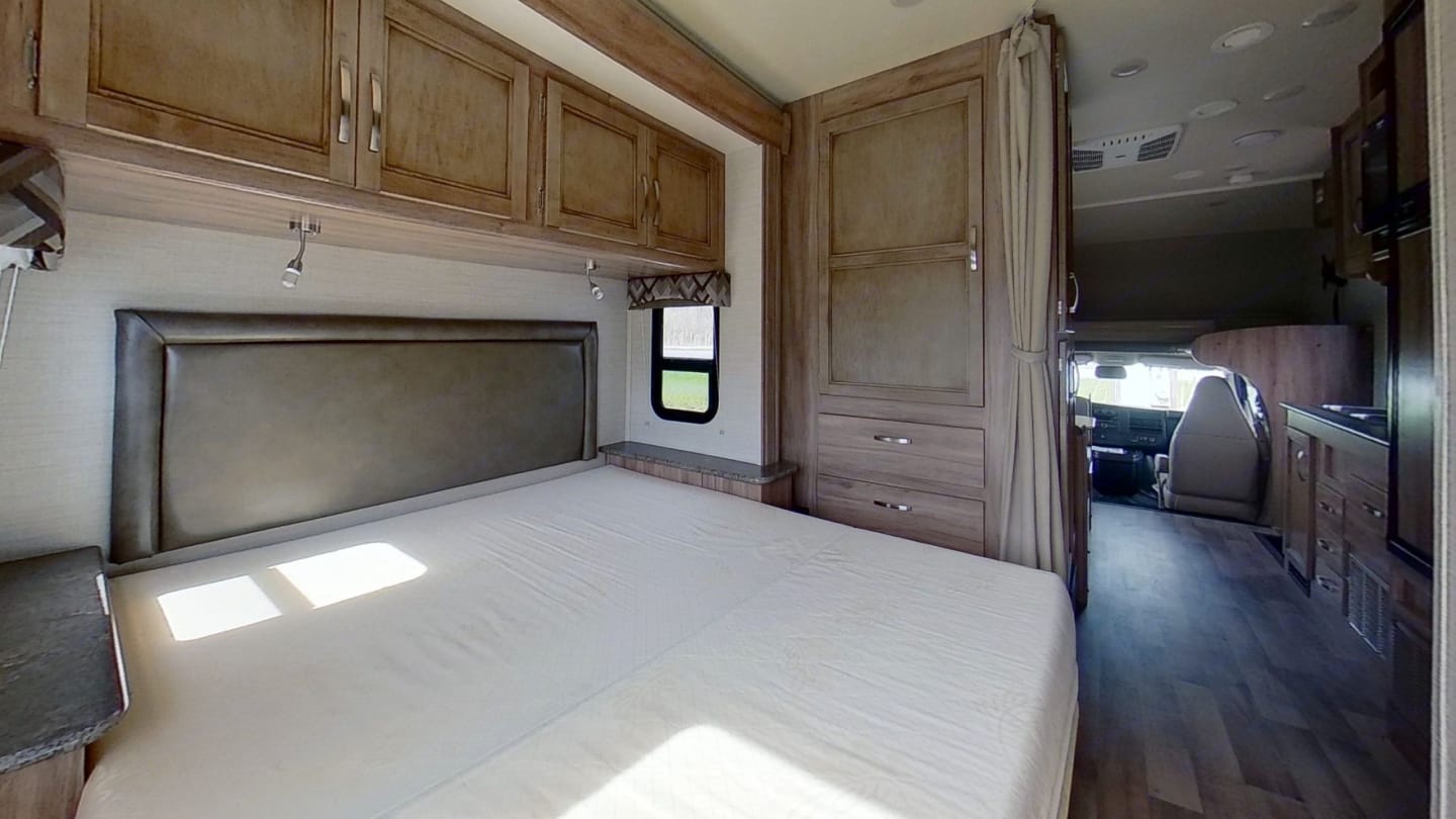 Spacious RV rental interior. Features a cozy bedroom with storage, leading to a modern kitchen and cab.. Jayco Redhawk SE 2021