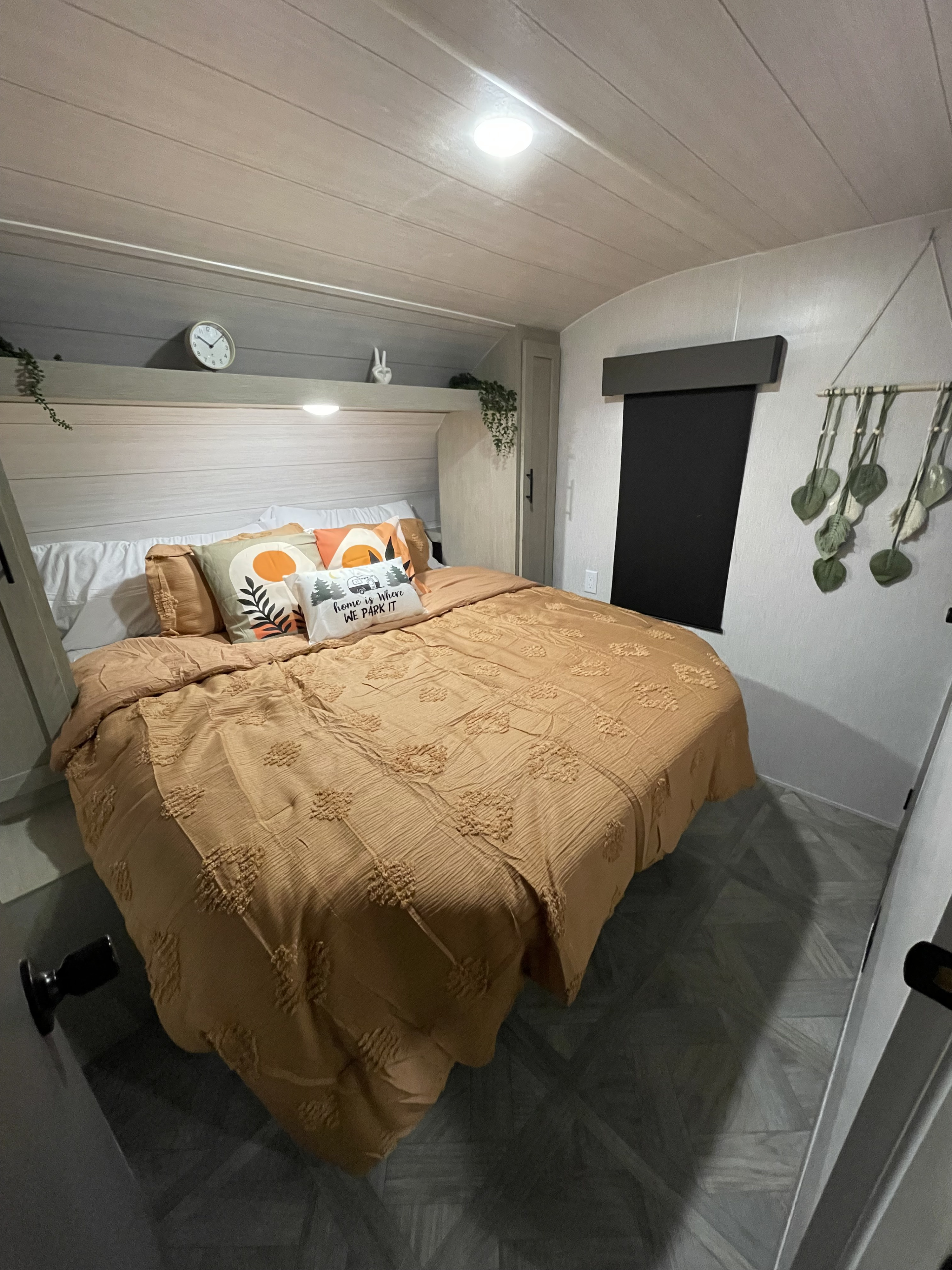 Cozy RV rental bedroom featuring warm orange bedding, decorative pillows, and modern decor, perfect for travel comfort.. Forest River Wildwood X-Lite 2024