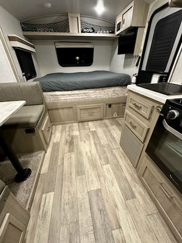 Cozy RV rental interior: featuring a bed, dinette, and compact kitchen, ready for your next road trip.. Forest River Rockwood Geo Pro 2022