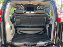 Rear view of a spacious conversion van interior, ideal for RV rental travel. The flat cargo area with a folded-down bench seat provides ample storage.. gmc savana 2500 explorer 2023