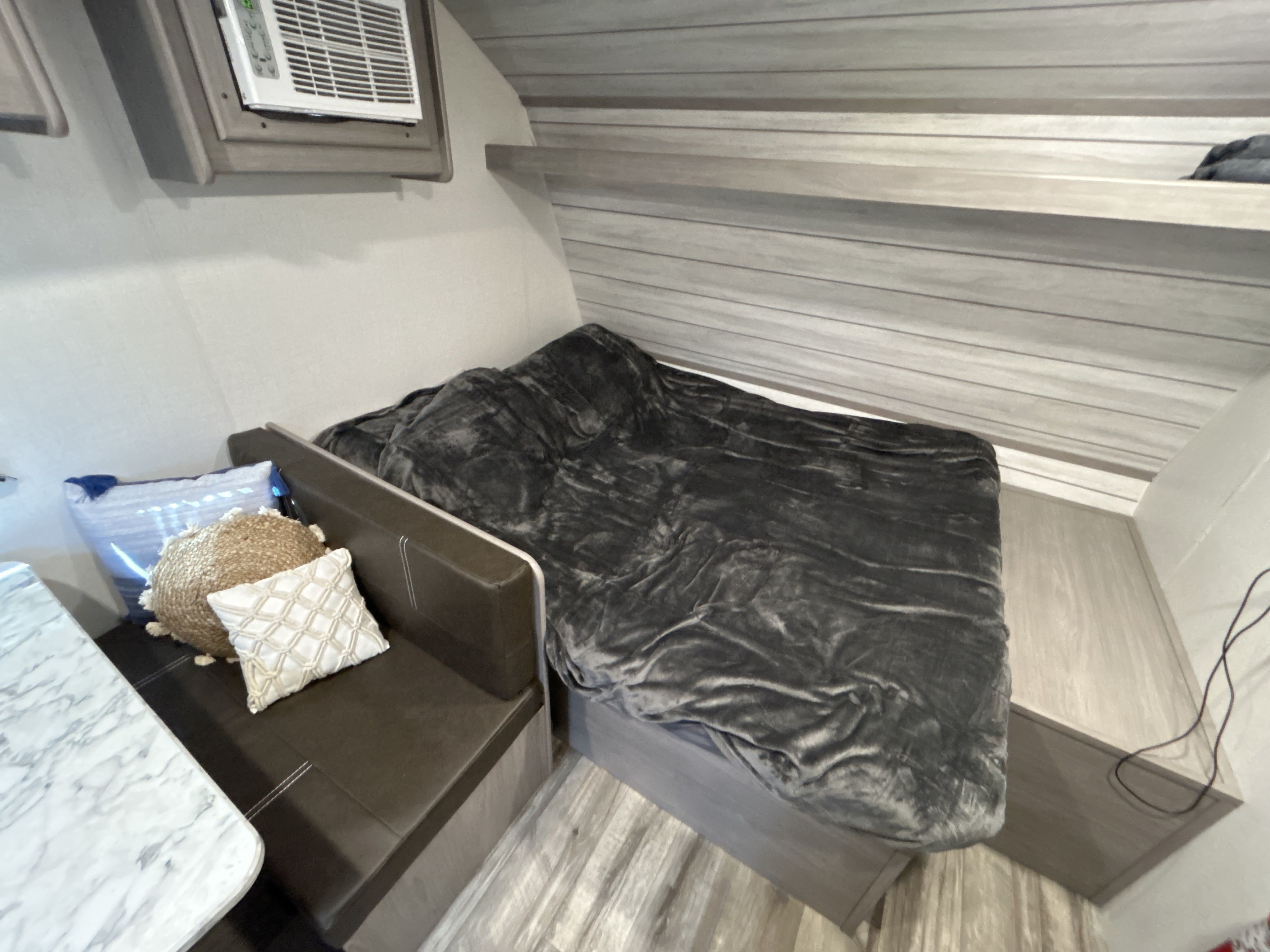 Cozy RV rental interior featuring a bed, dinette, and AC unit, ideal for travel.. Dutchmen Coleman Lantern 17B 2023