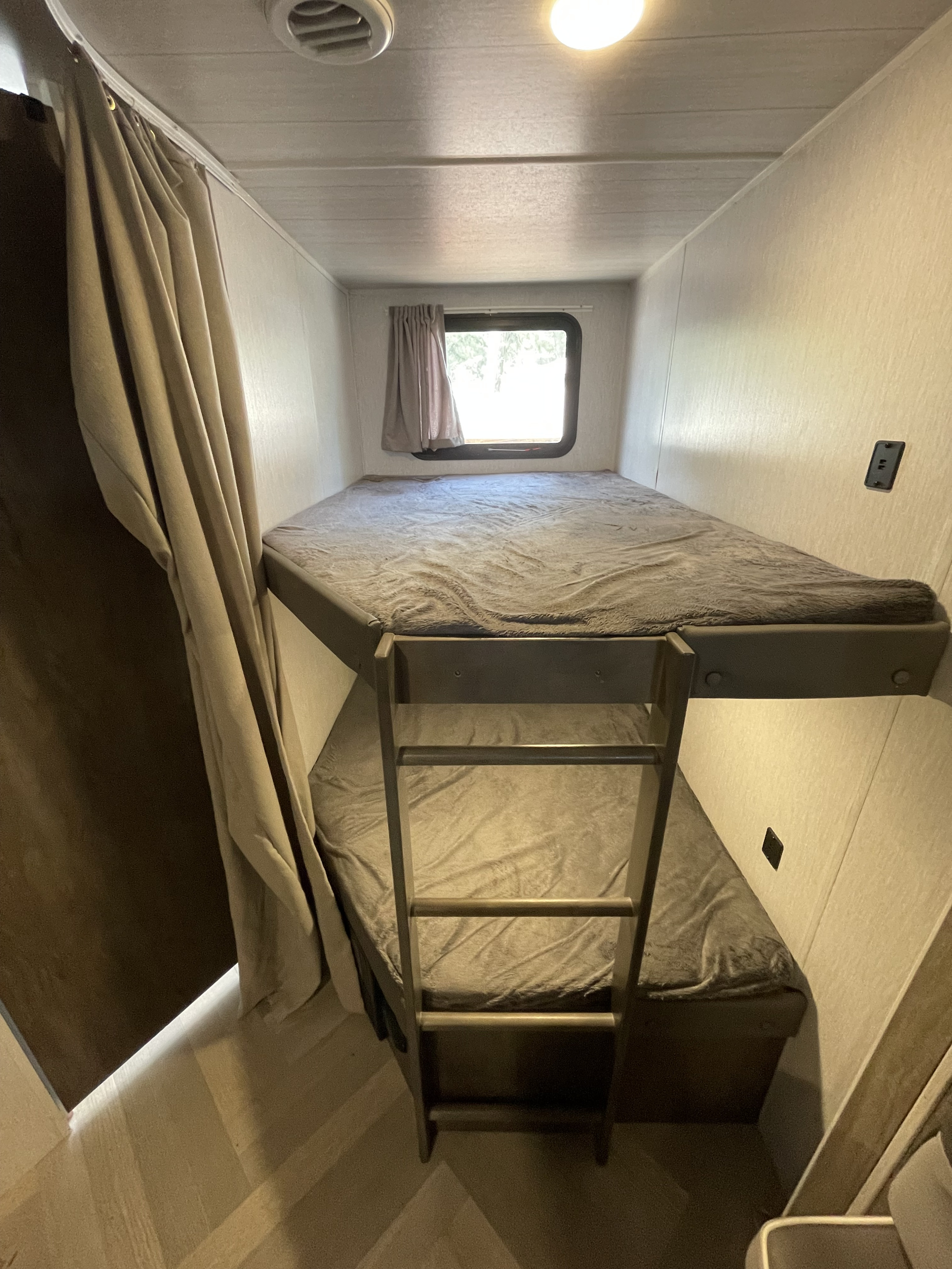 Cozy RV rental bunk beds with privacy curtain, window, and ladder, perfect for families.. Forest River Salem Cruise Lite 2022