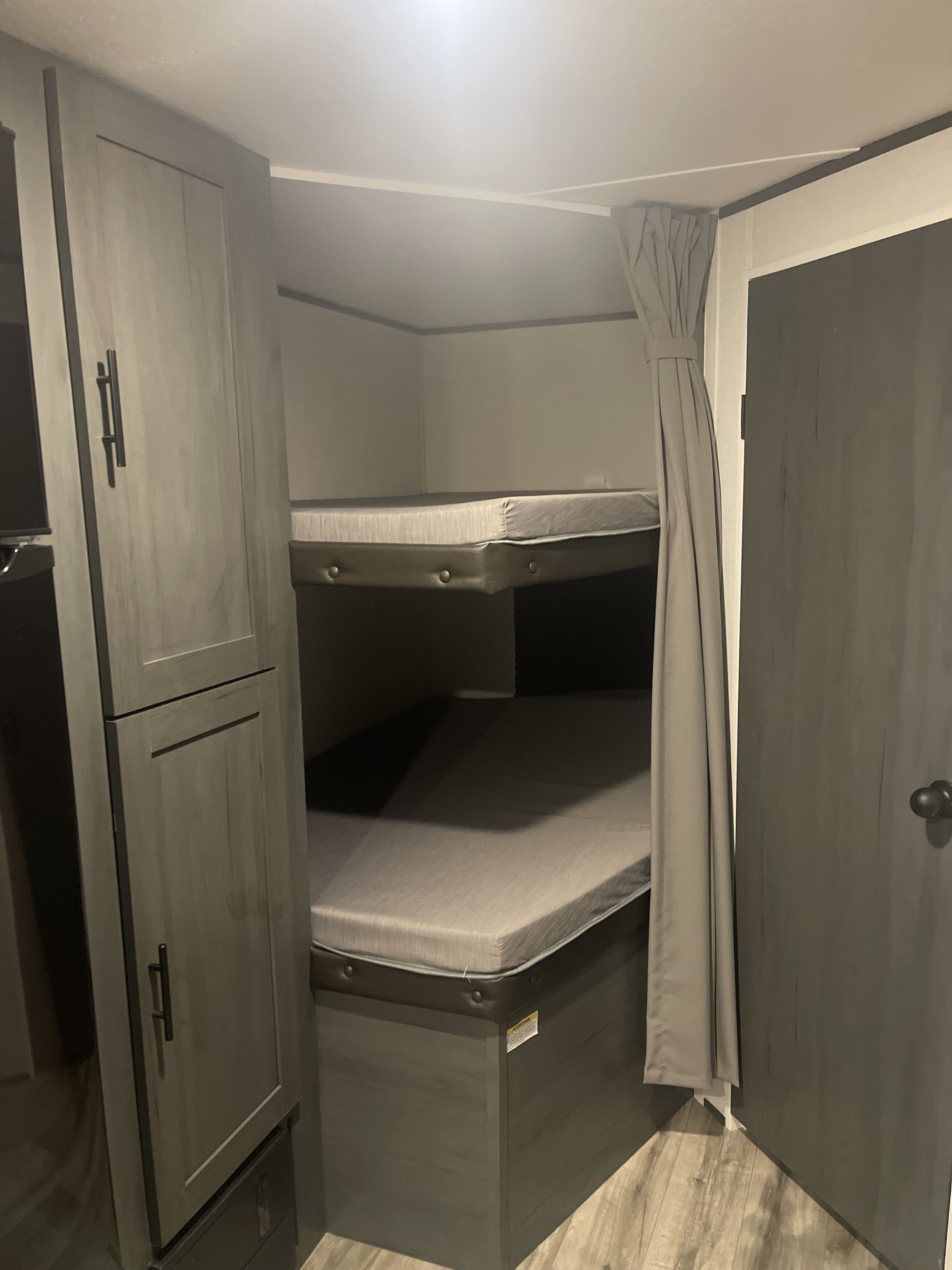 Explore this RV rental's interior: modern bunk beds provide sleeping space, with built-in storage and a private door.. Dutchmen 26bhc 2024