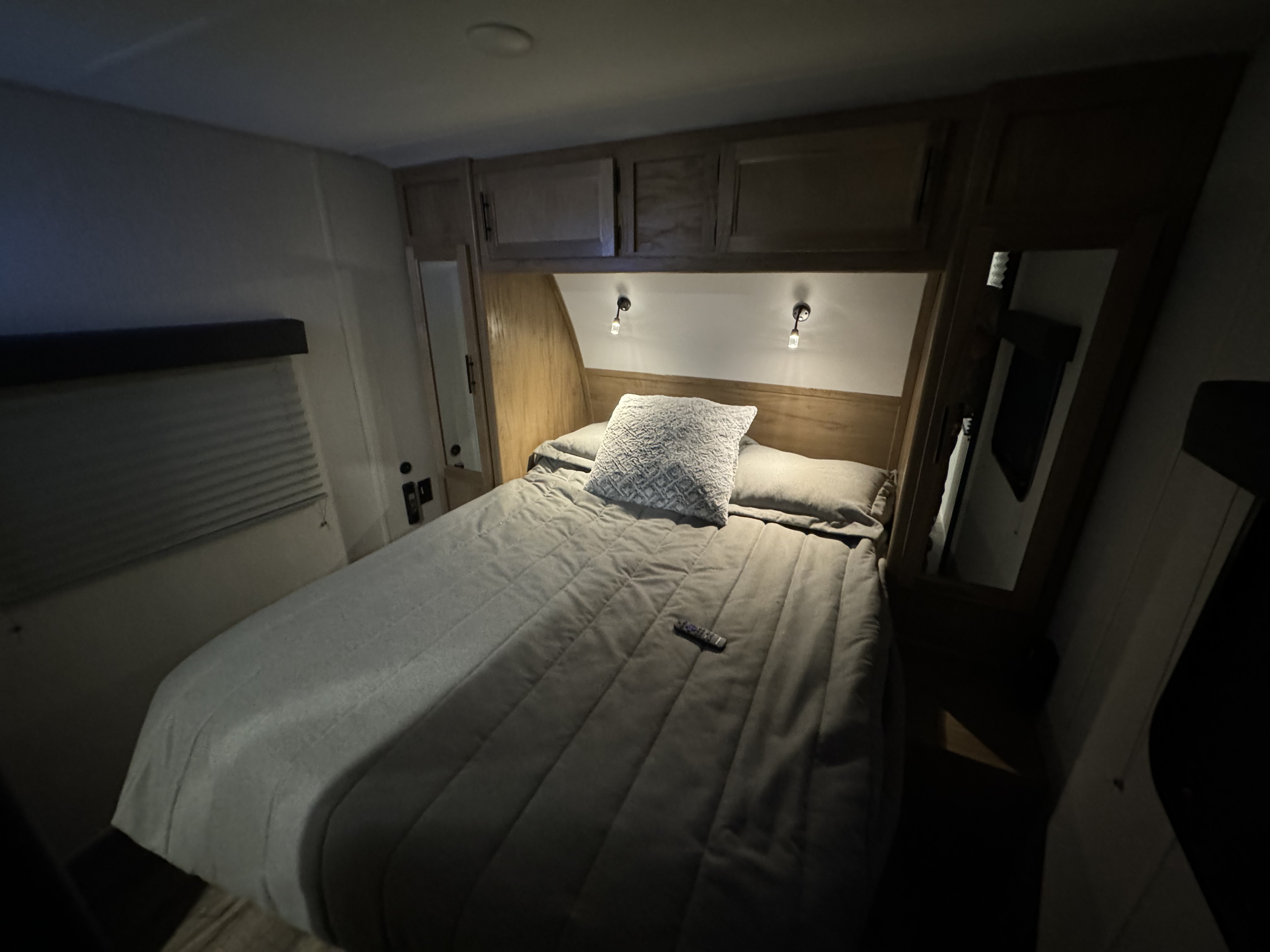 Cozy RV rental bedroom with a comfortable bed, grey bedding, overhead storage, and two reading lights.. Forest River Cherokee Grey Wolf 2024