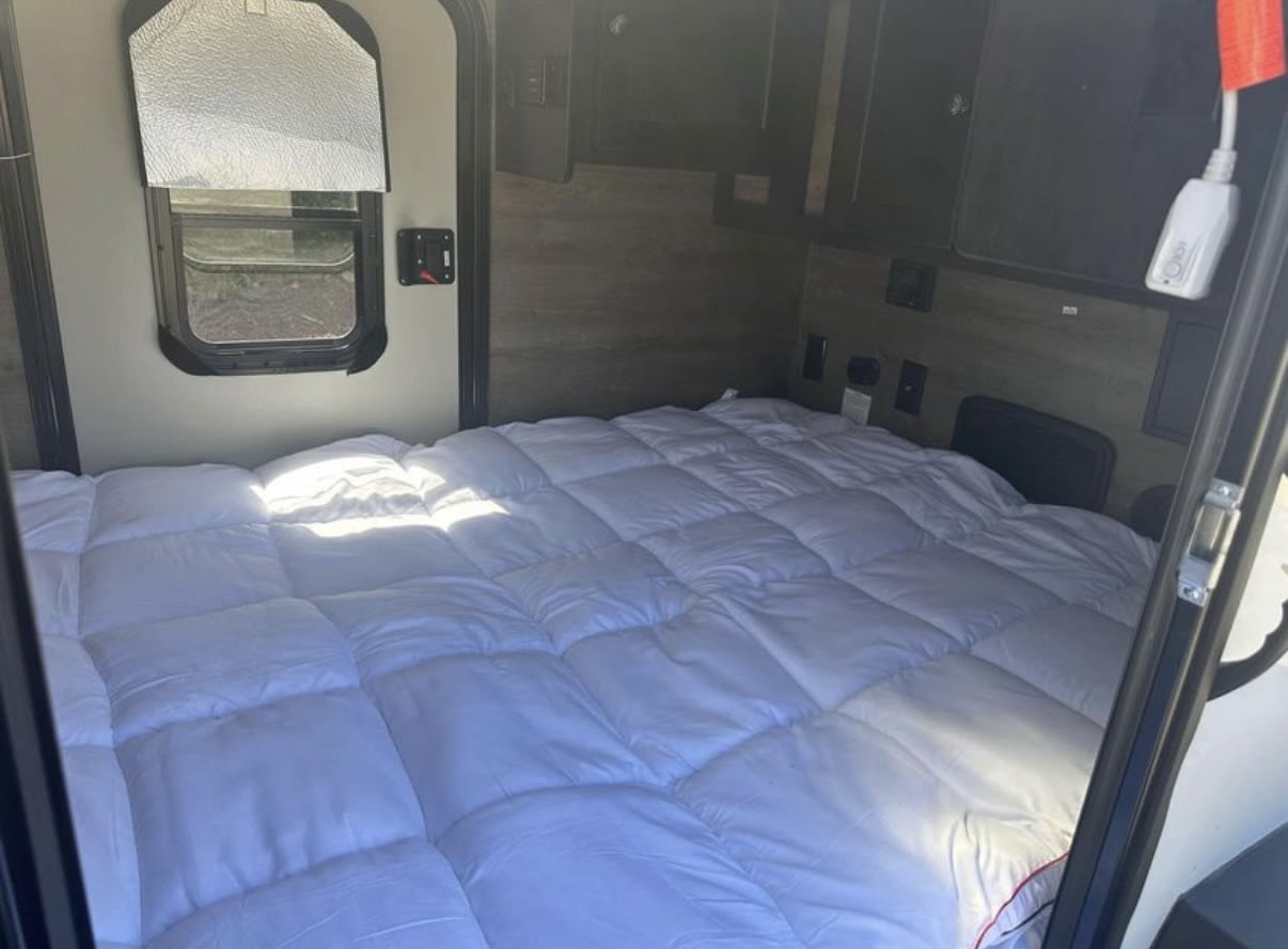 Inside this RV rental: a comfortable, plush white bed with a quilted comforter filling the compact sleeping area.. Braxton Creek Free Solo 2022