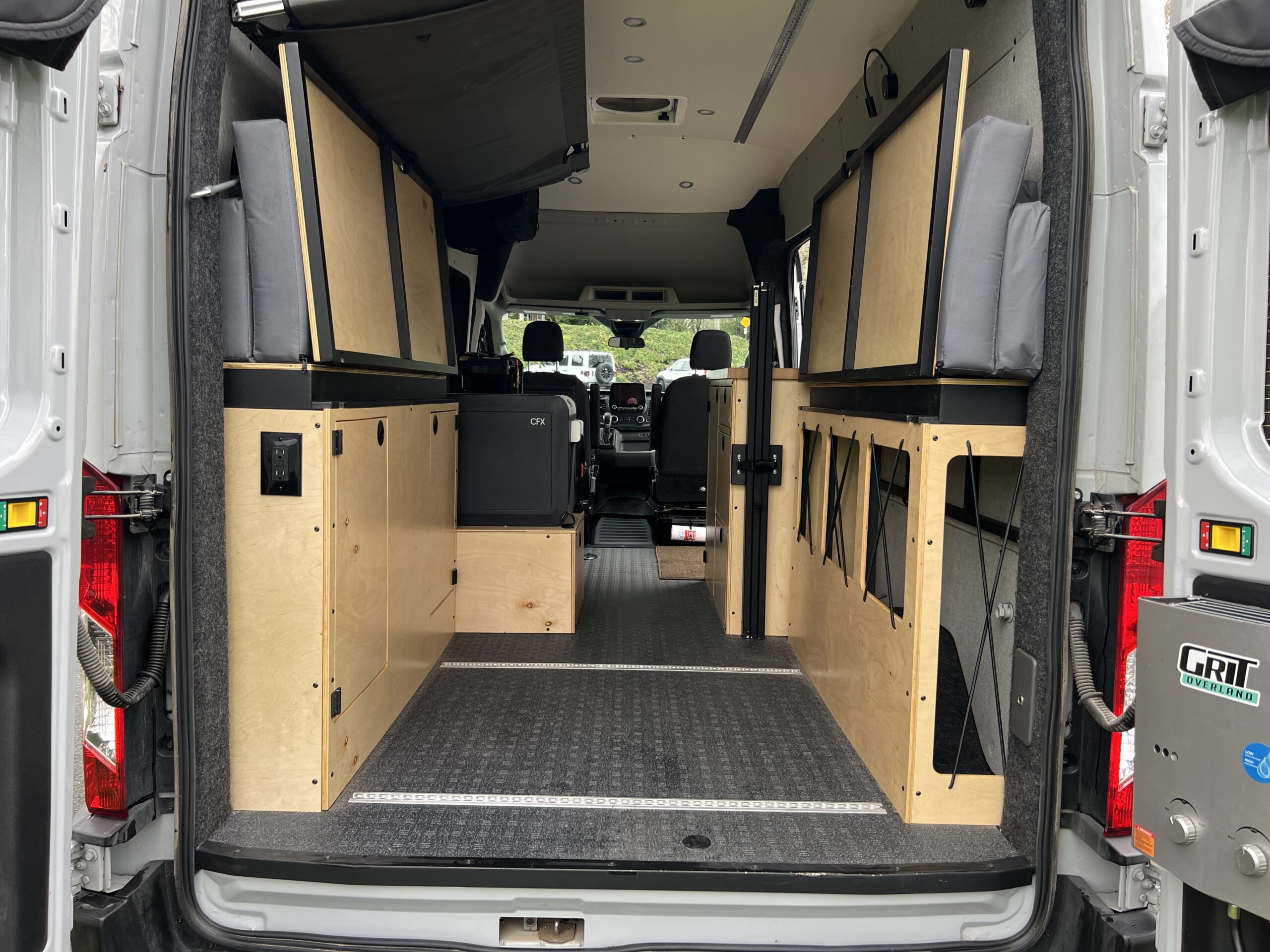 Custom rv rental camper van interior: modular plywood storage, fridge, portable shower, and bed platforms.. Grit Overland Go Terra 2021