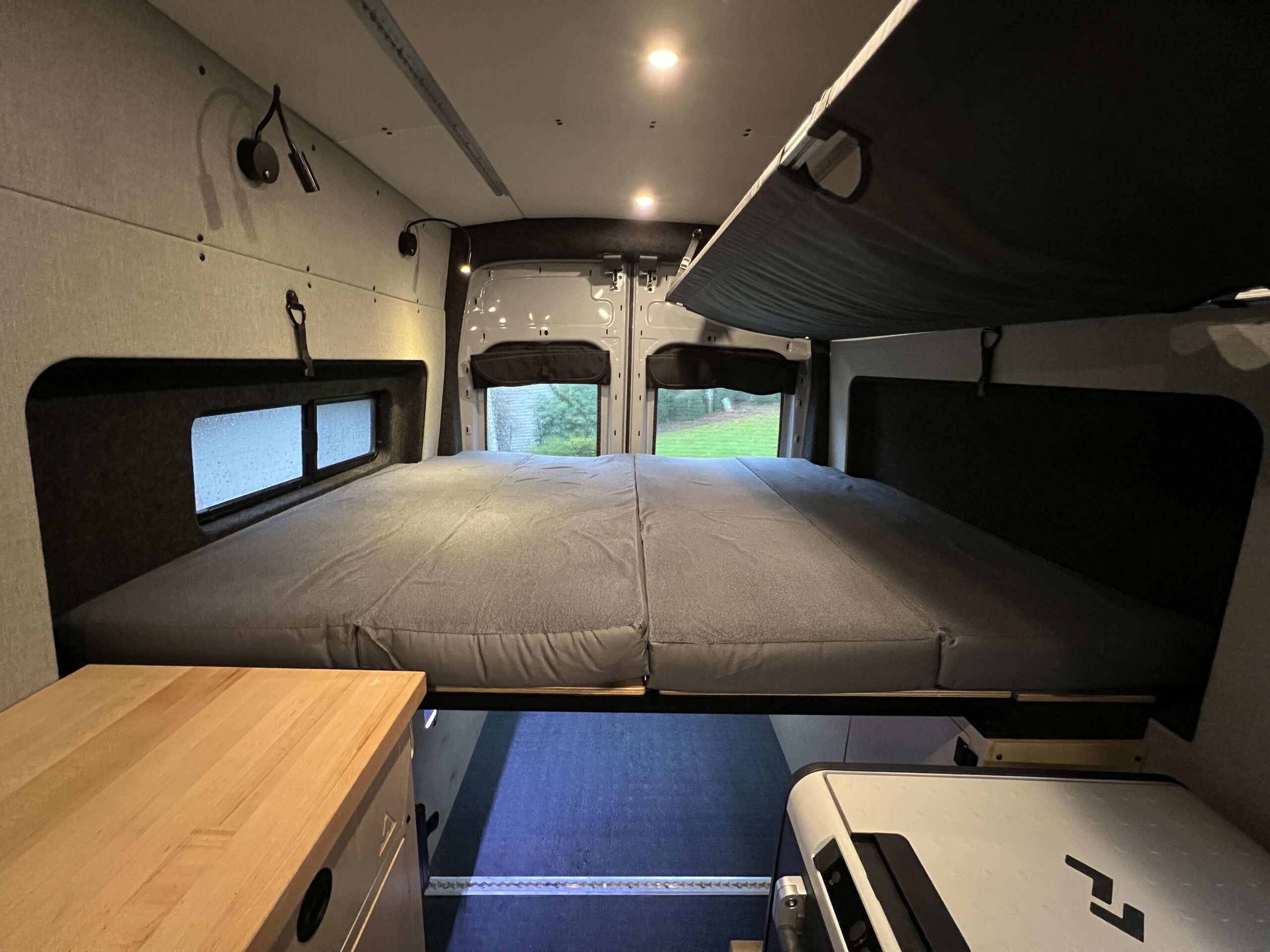 Spacious RV rental interior with a comfy bed, windows with a view, and integrated storage, ideal for your next journey.. Grit Overland Go Terra 2021