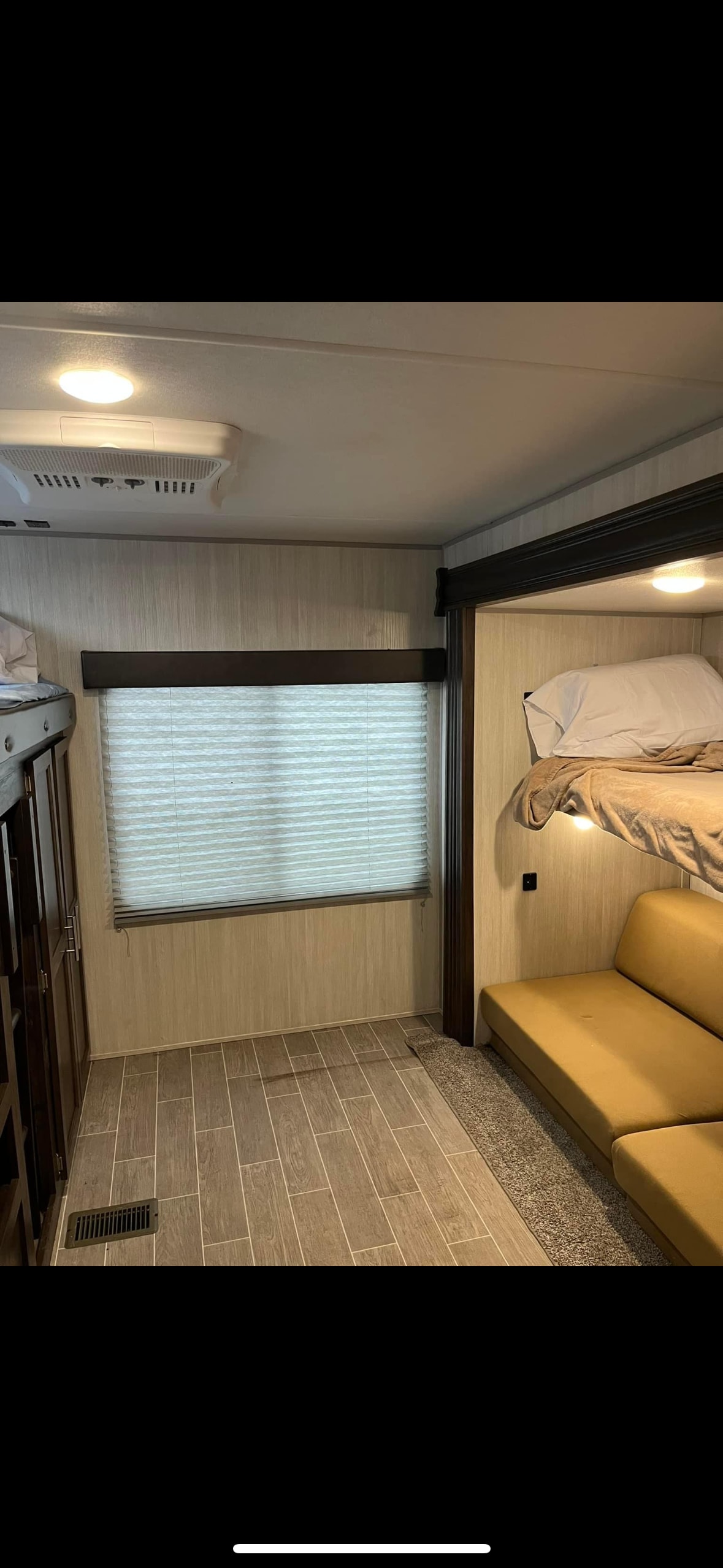 Cozy RV rental interior featuring bunk beds, a lower sofa bed, window with blinds, and wood-look flooring.. Forest River Cherokee 2019
