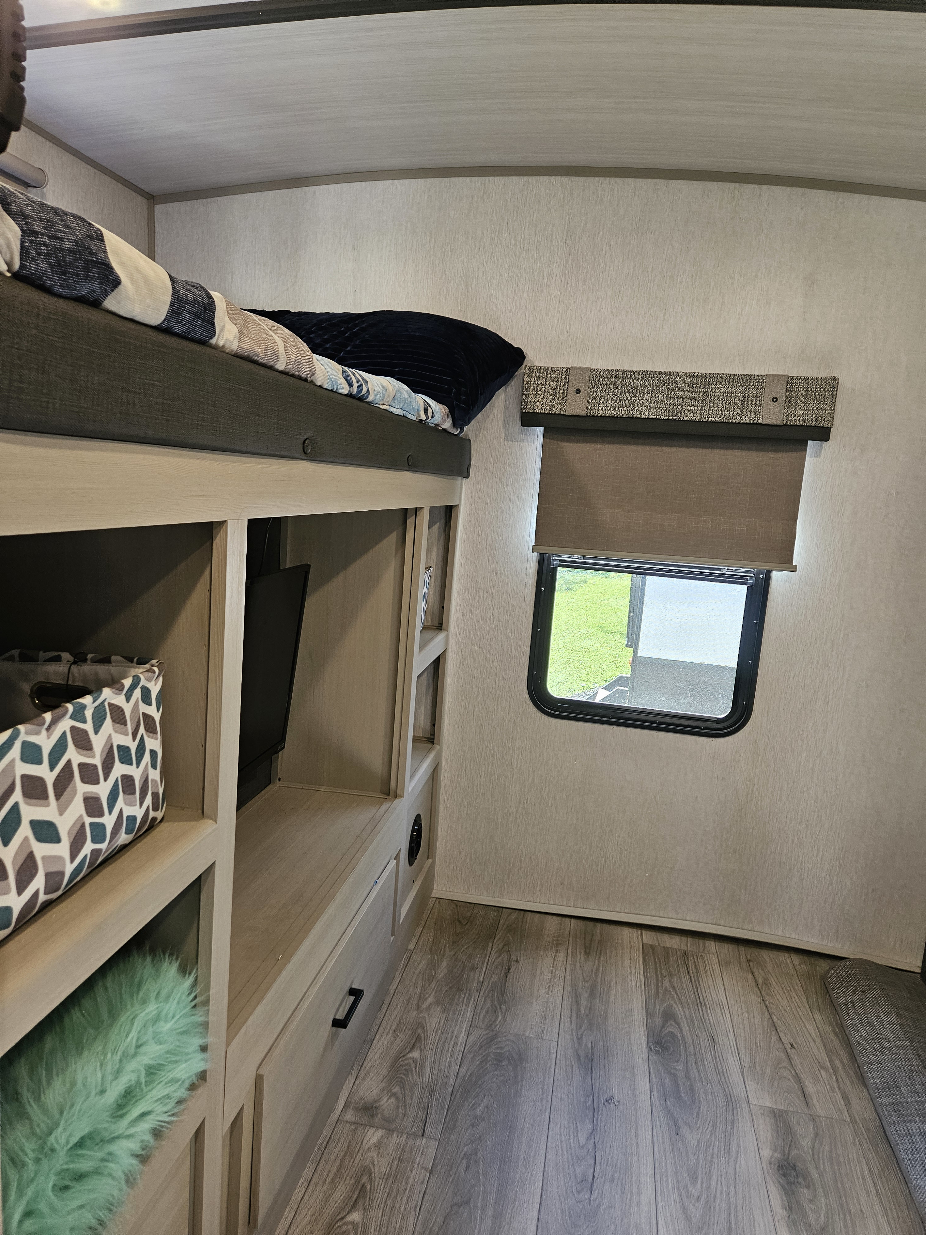 Cozy RV rental interior with bunk beds, storage, TV, and a window view. Perfect for family trips!. Forest River Heritage Glen 2023