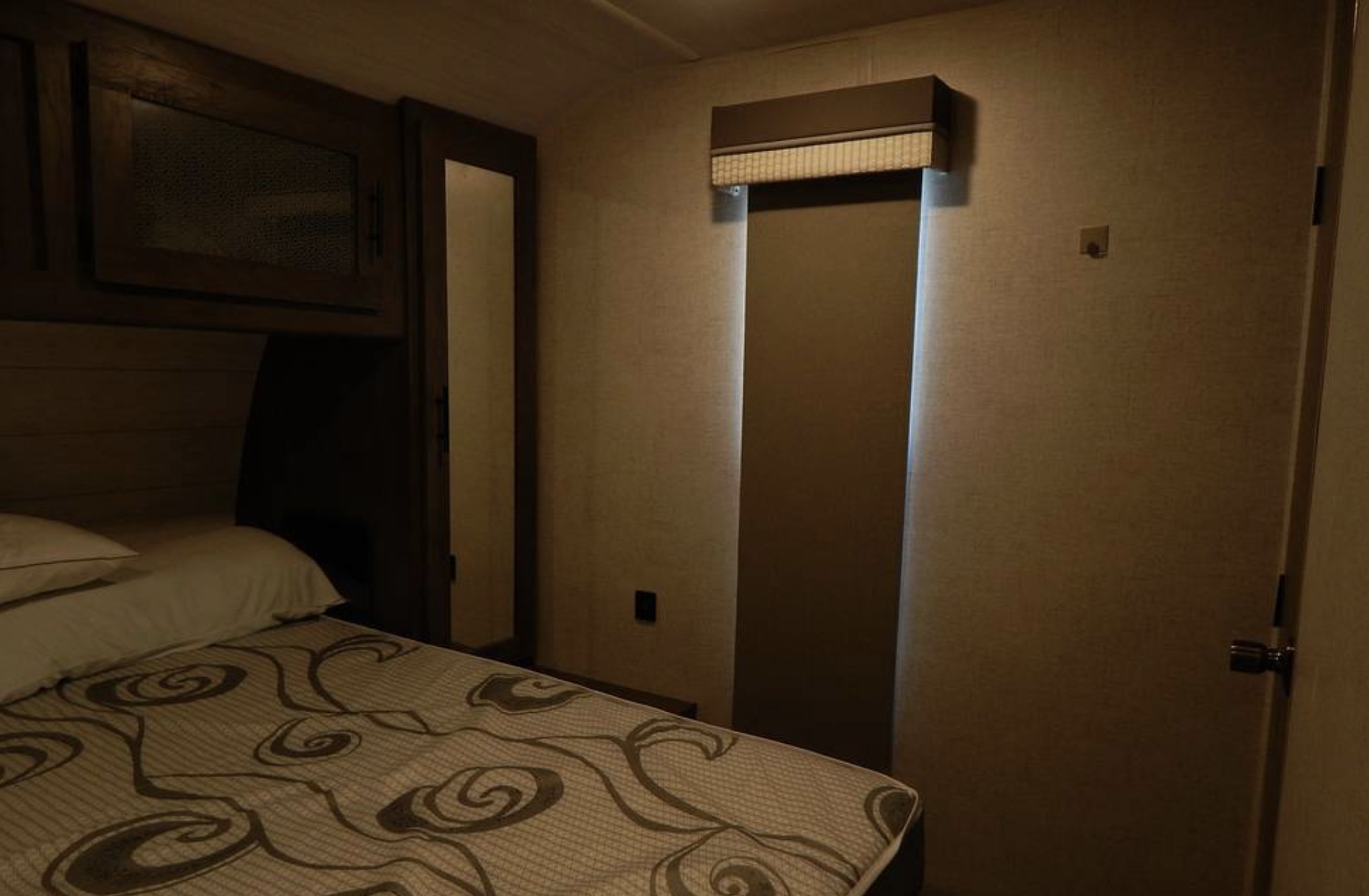 Experience comfort in this RV rental bedroom. Features a bed, overhead cabinets, and illuminated window, ideal for your next trip.. Forest River Salem 2021