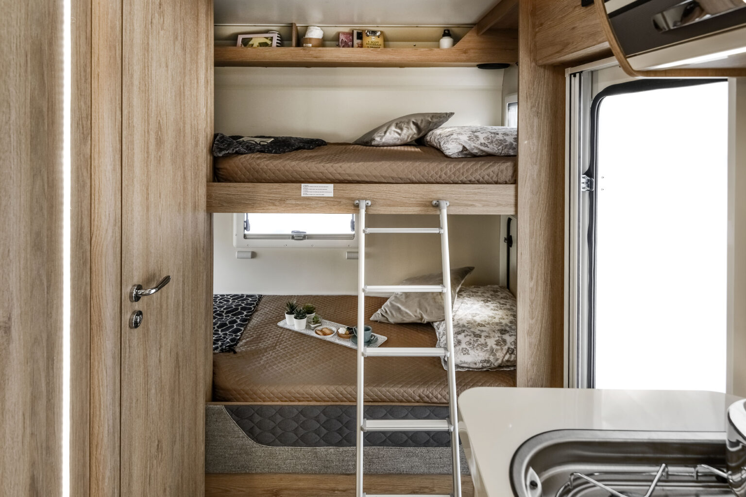 Cozy RV rental interior featuring comfortable bunk beds, a compact kitchen, and inviting decor, perfect for family adventures.. Roller Team 707 Auto Roller 2025