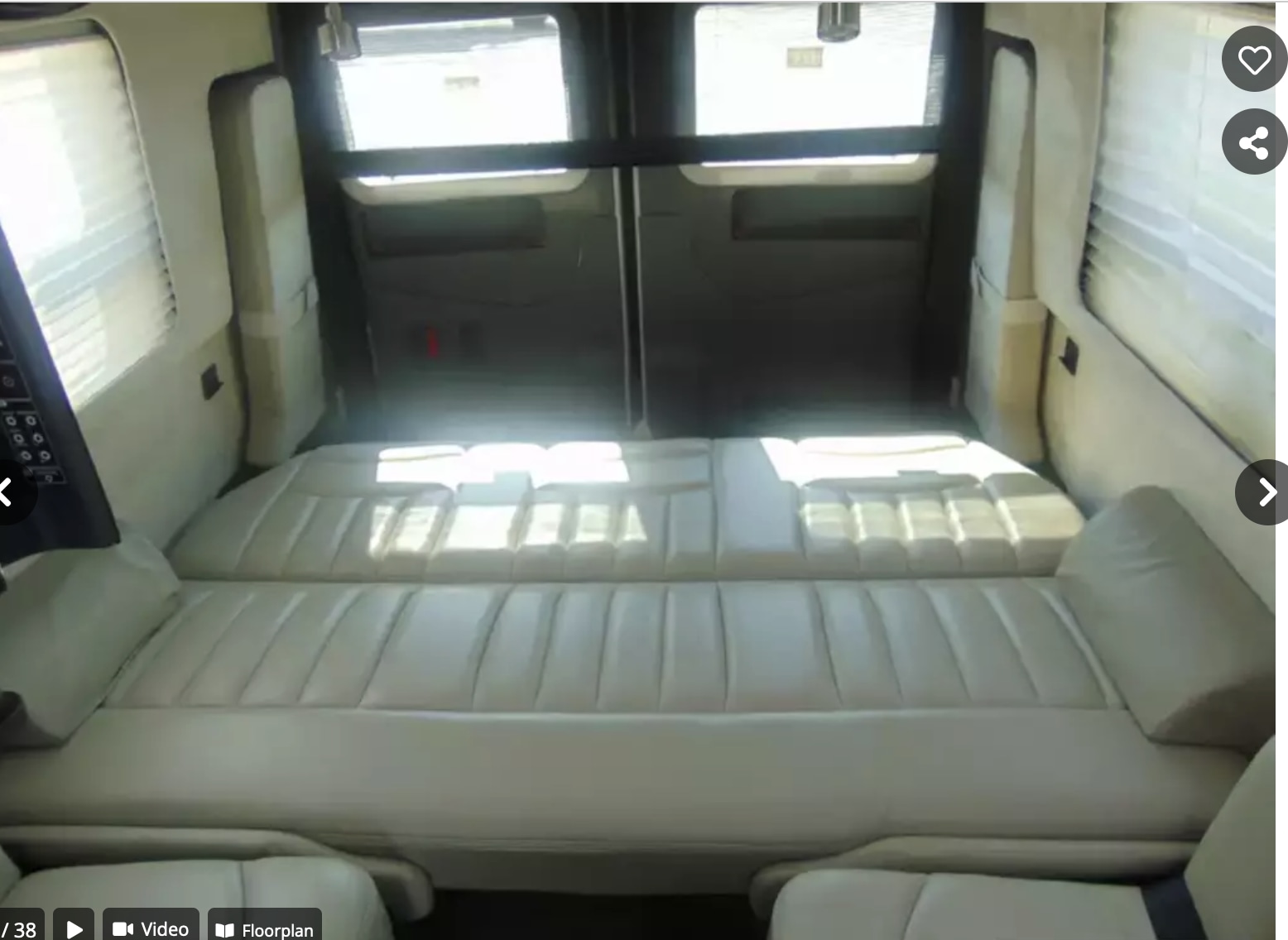 RV rental interior shows a spacious cream-colored convertible bed/seating area in a camper van, extending to rear doors.. Airstream Interstate 2014