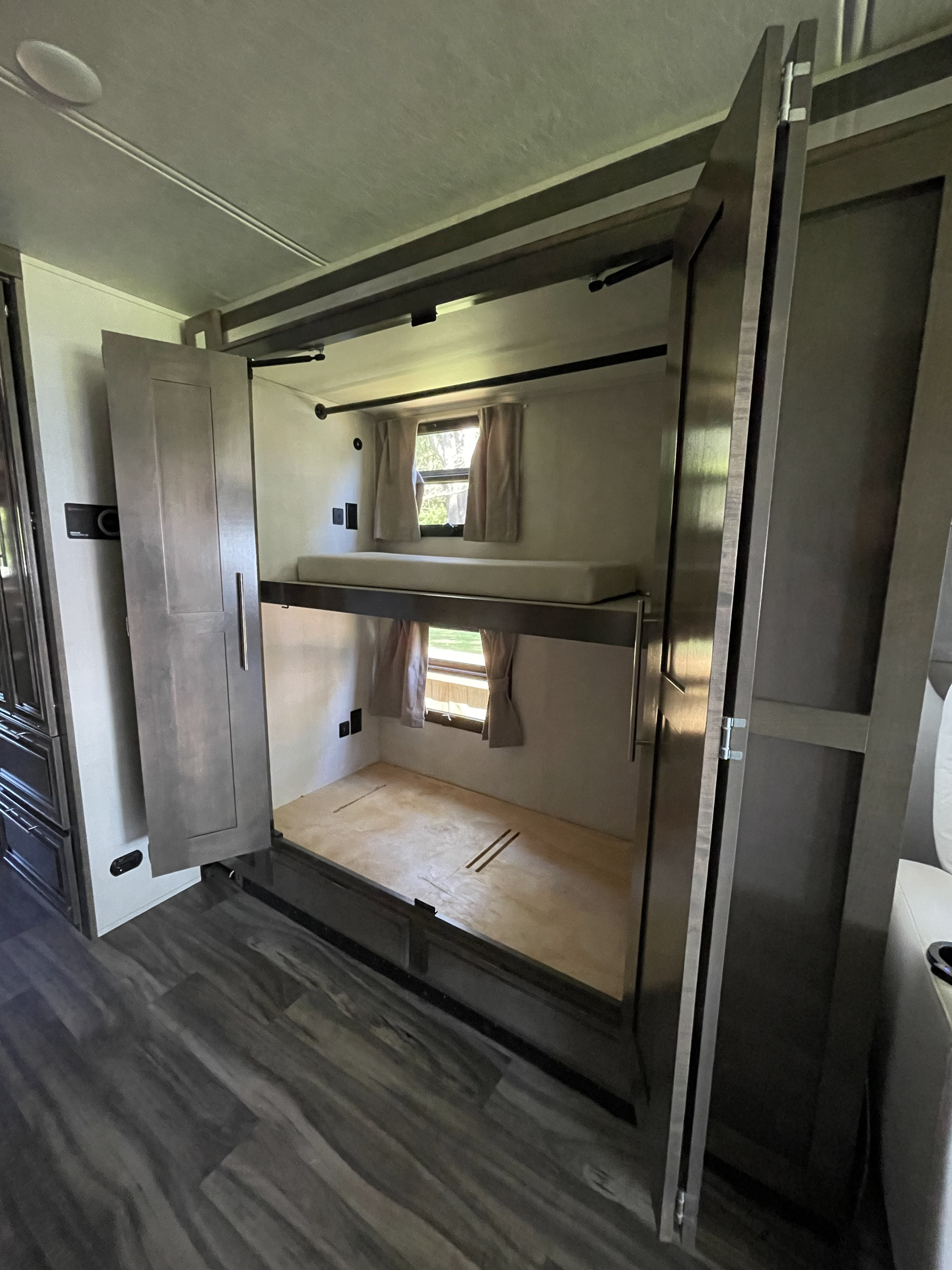 RV rental interior shows sleek bunk beds. Upper bunk has a mattress, lower is an empty wooden base with window views.. Georgetown GT7 2022
