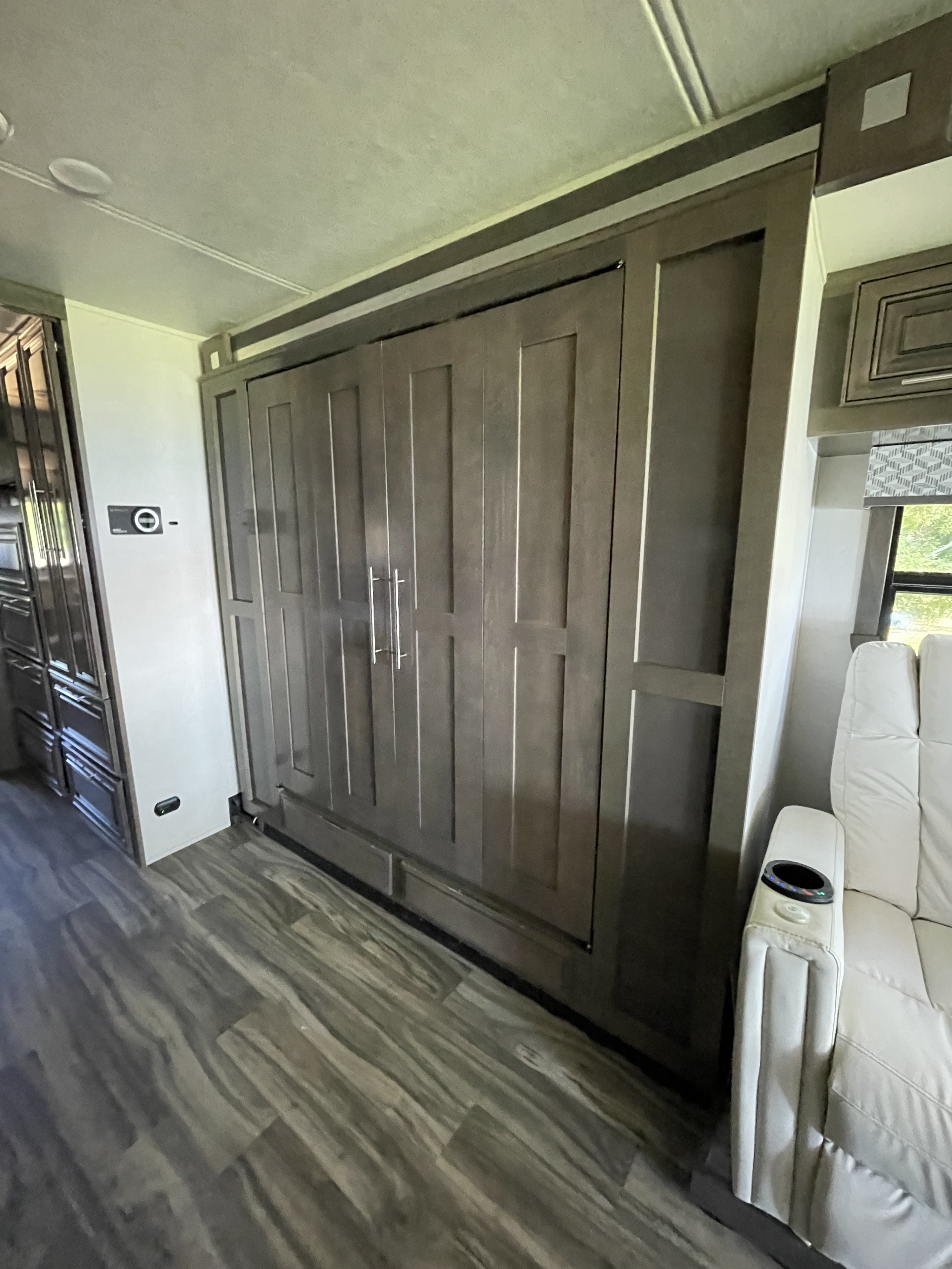 Spacious RV rental interior with modern dark cabinetry, a control panel, and a comfortable white recliner.. Georgetown GT7 2022