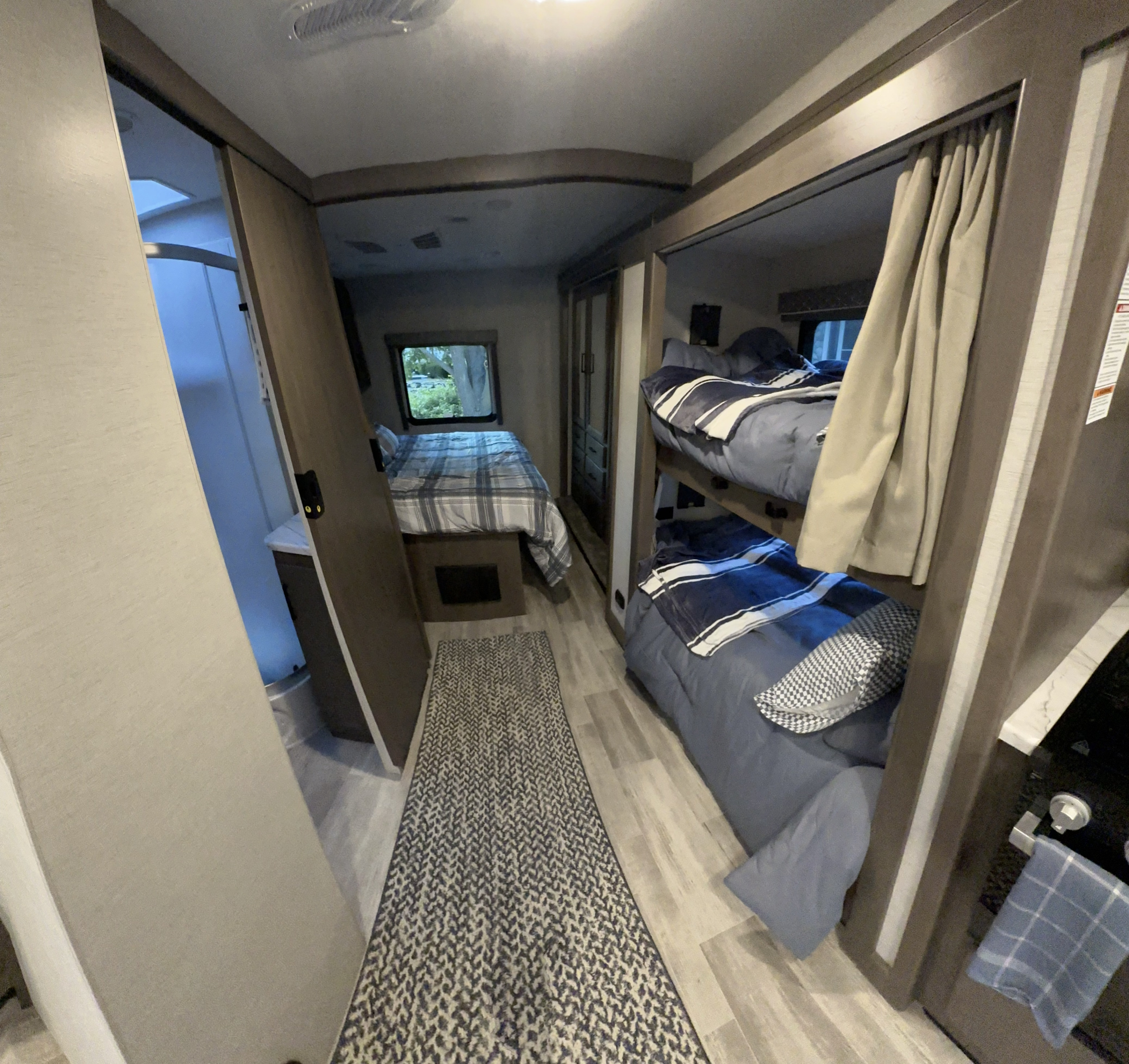 Experience comfort in this RV rental! Features a main bedroom with a plaid bed, blue bunk beds, and a full bathroom.. Thor Freedom Traveler 2024