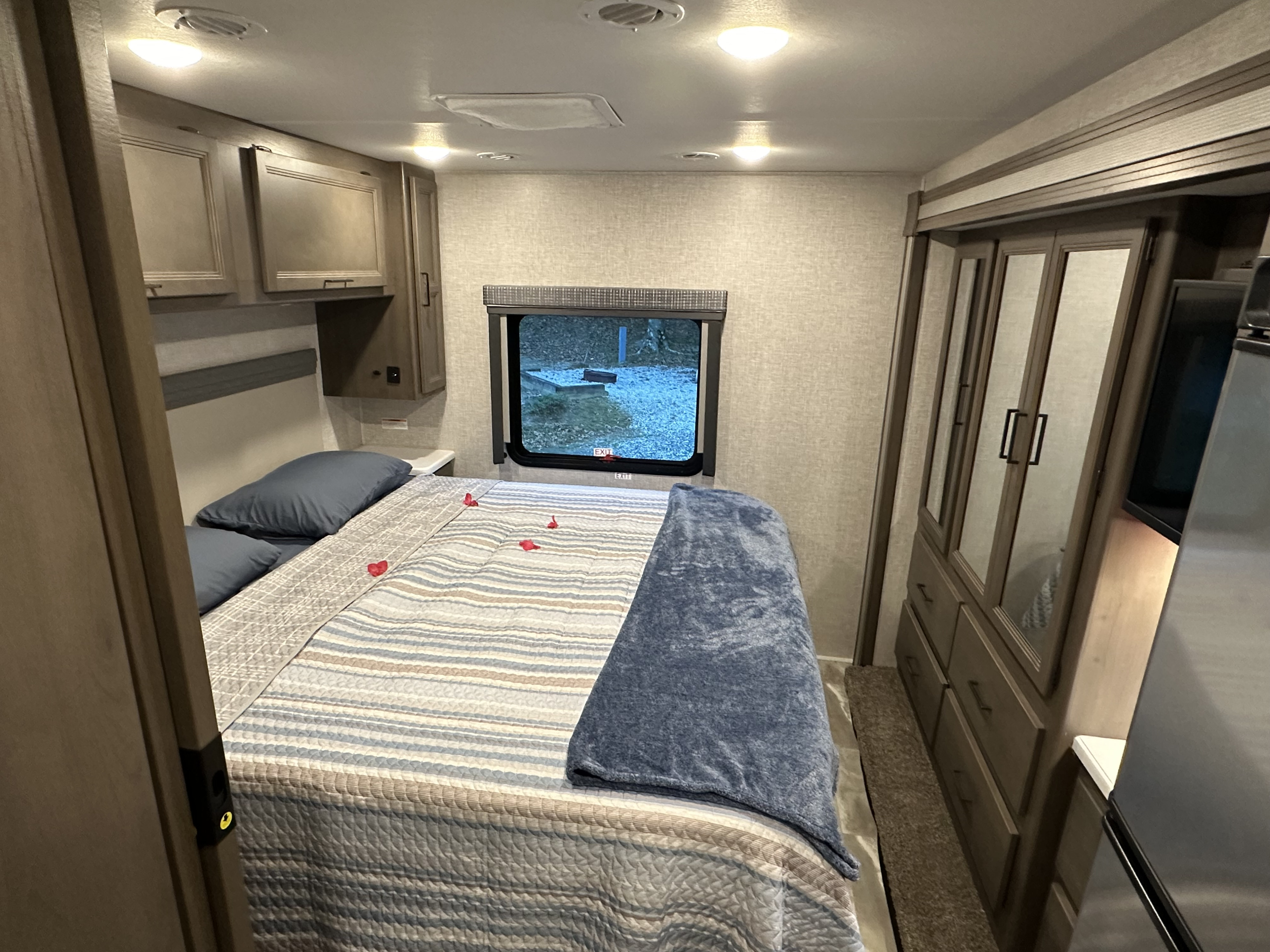Inviting rv rental bedroom: comfy bed with red hearts, window view of snowy campsite, wardrobe & overhead storage.. Thor Windsport 2023