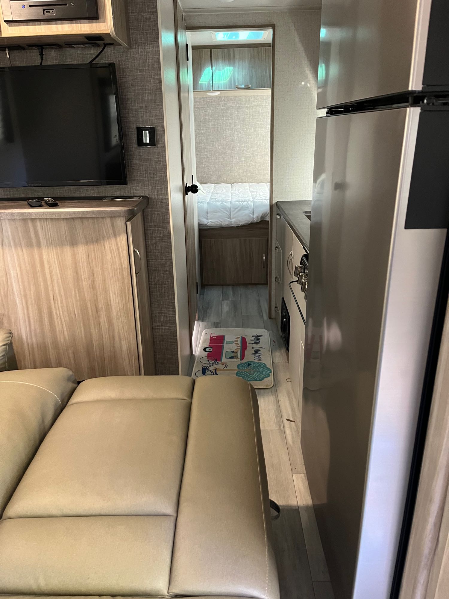 Inside our RV rental: a compact layout featuring a comfortable living area, kitchen, and a bedroom beyond.. Winnebago Minnie Winnie 2022