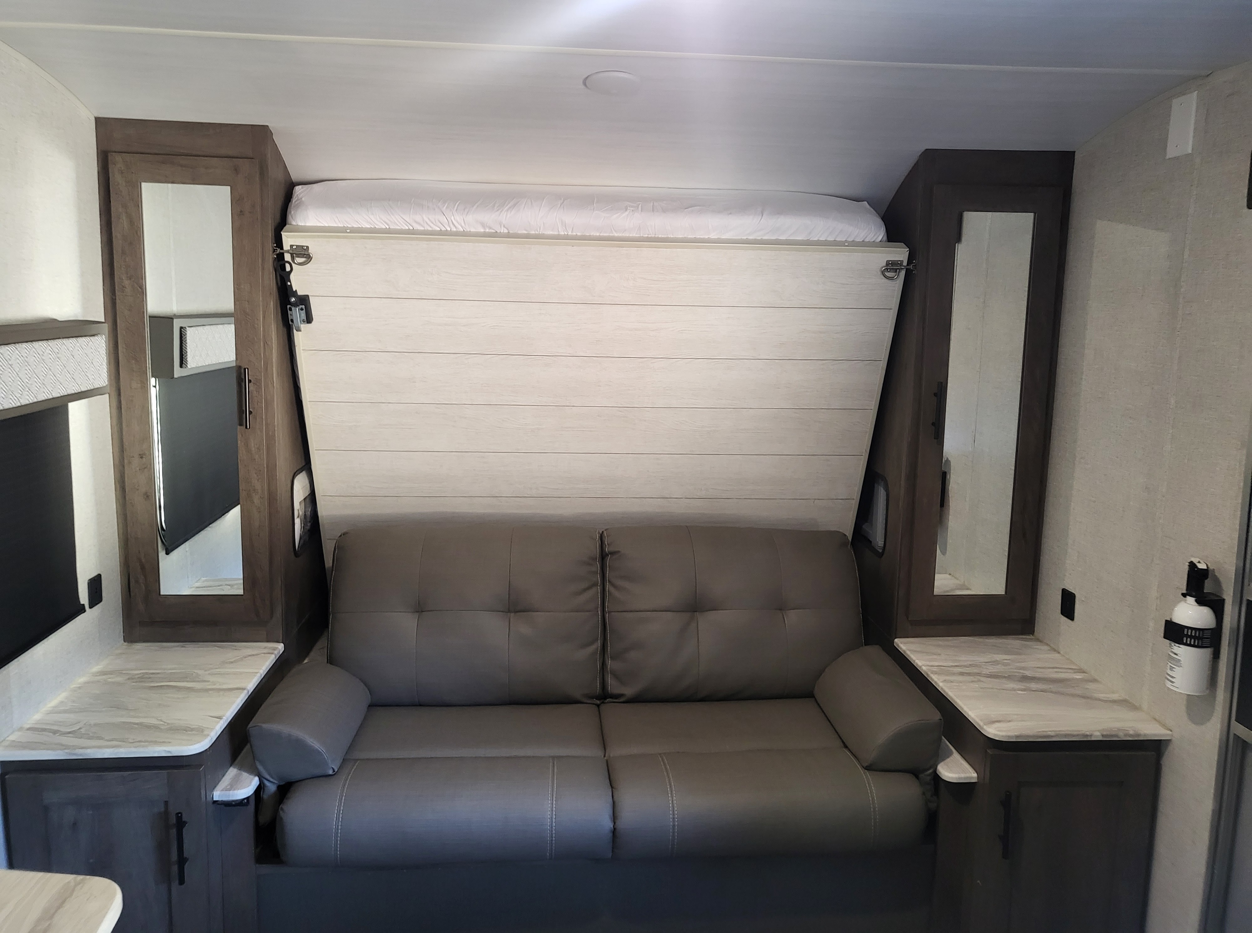 RV rental interior: clever design with a pull-down murphy bed over a sofa, flanked by mirrored storage.. Forest River Salem Cruise Lite 2020