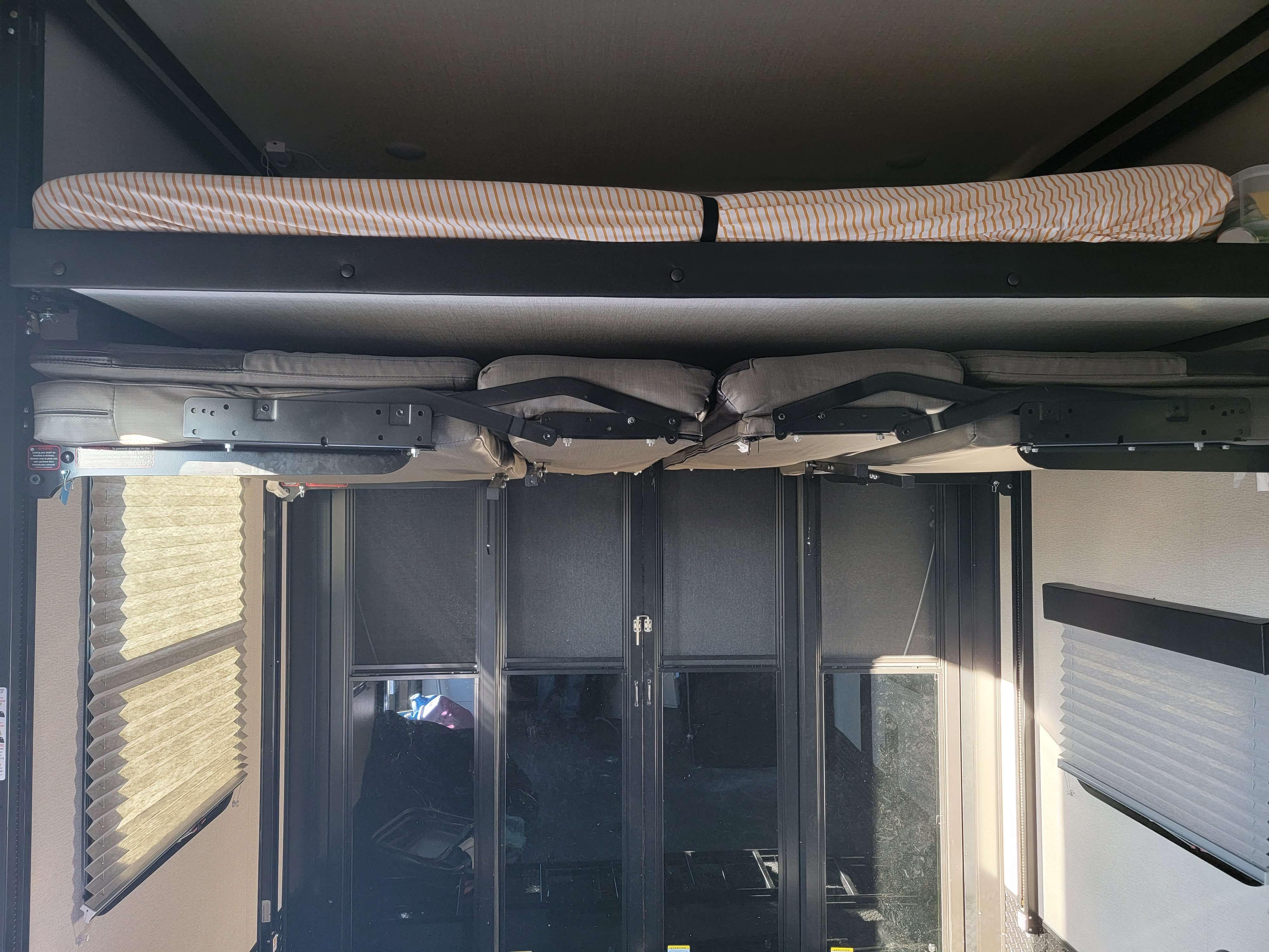 RV rental's spacious interior: Upper bunk bed, convertible lower seating, and rear ramp door. Ideal for family camping trips.. Grand Design Momentum 2022