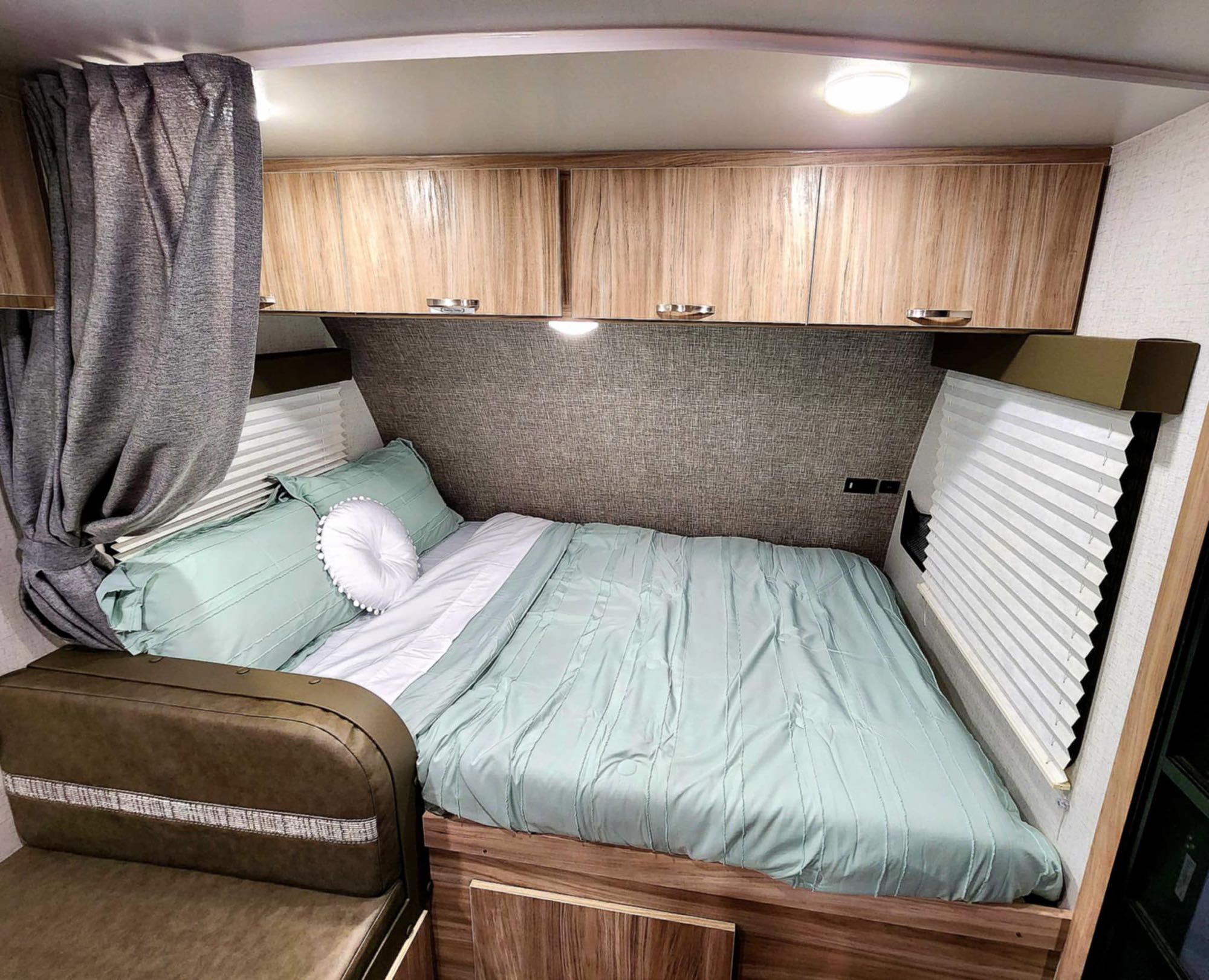 RV rental: Cozy bedroom with green bedding, overhead storage, window blinds, and curtain, plus a comfy seat for travel.. Winnebago Micro Minnie 1800BH 2022
