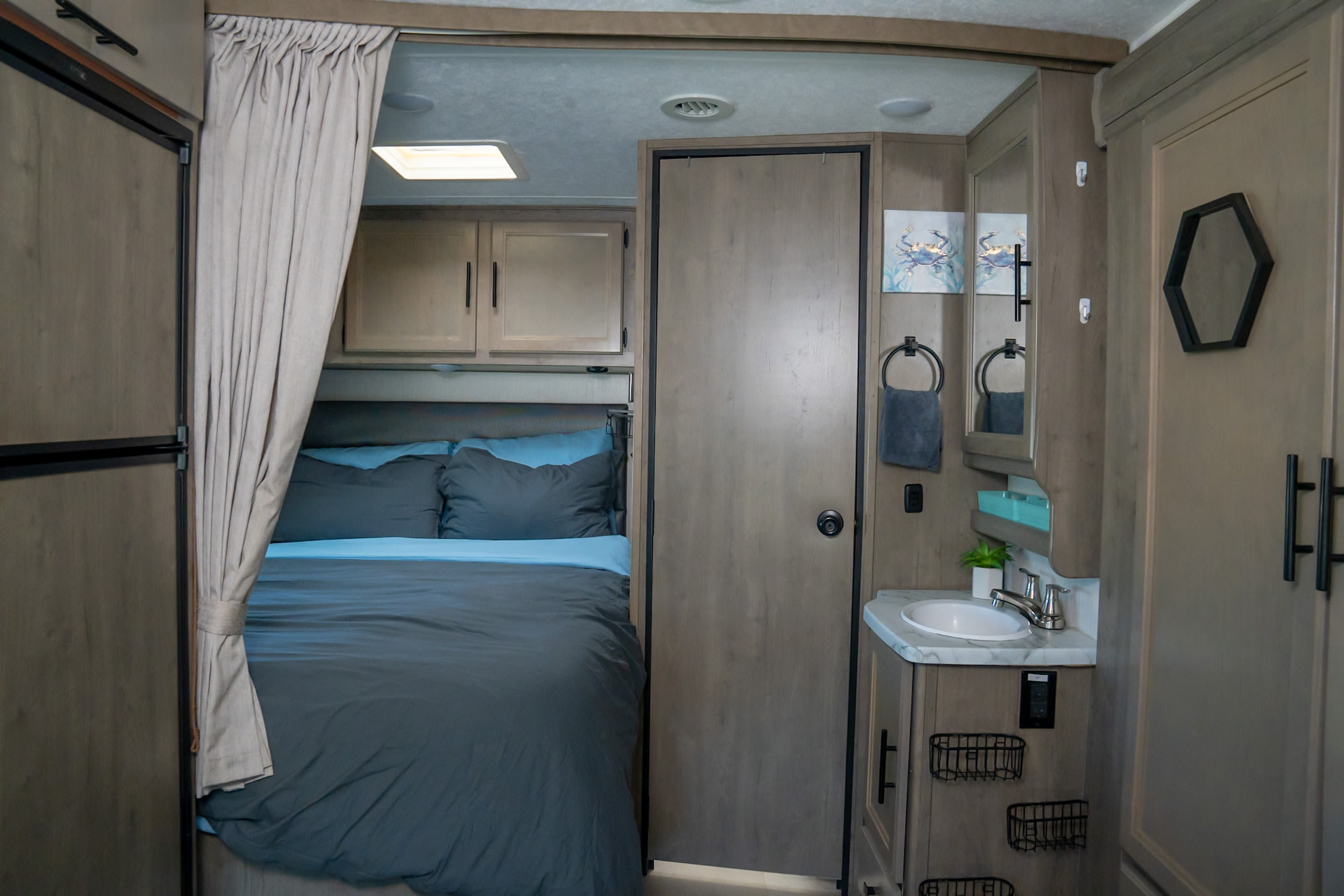 Well-appointed RV rental interior featuring a comfortable bedroom, private vanity with sink, and ample storage.. Coachmen Prism 2020