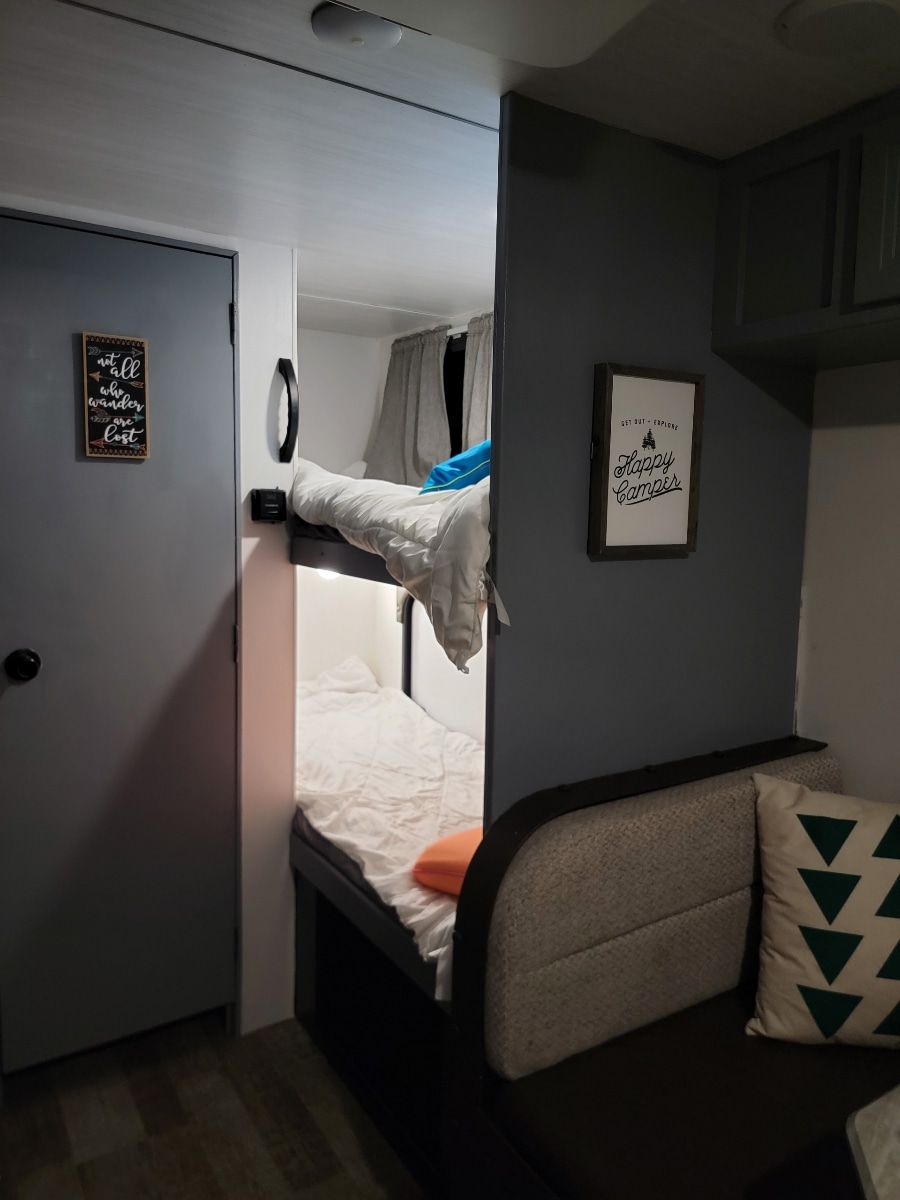 Step inside this inviting RV rental: a modern interior featuring comfy bunk beds and a cozy dinette with decorative pillows.. Winnebago Minnie Winnie 2021