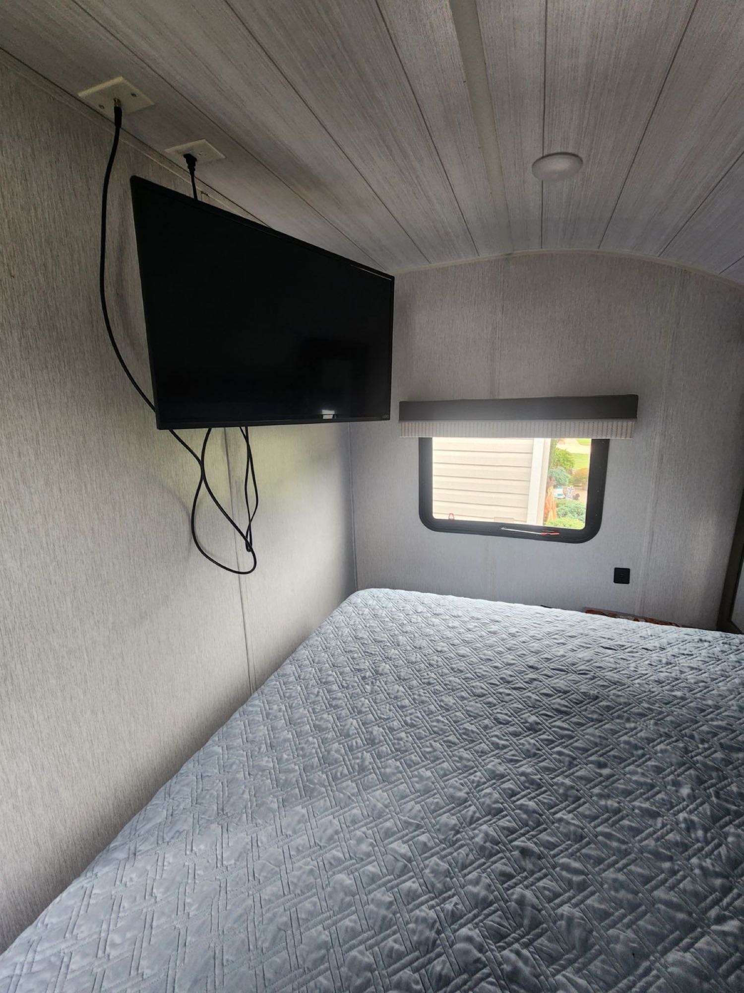 RV rental bedroom with a wall-mounted TV and a comfortable, light blue quilted bed. A cozy and compact space for travel.. Forest River Salem Cruise Lite 2022