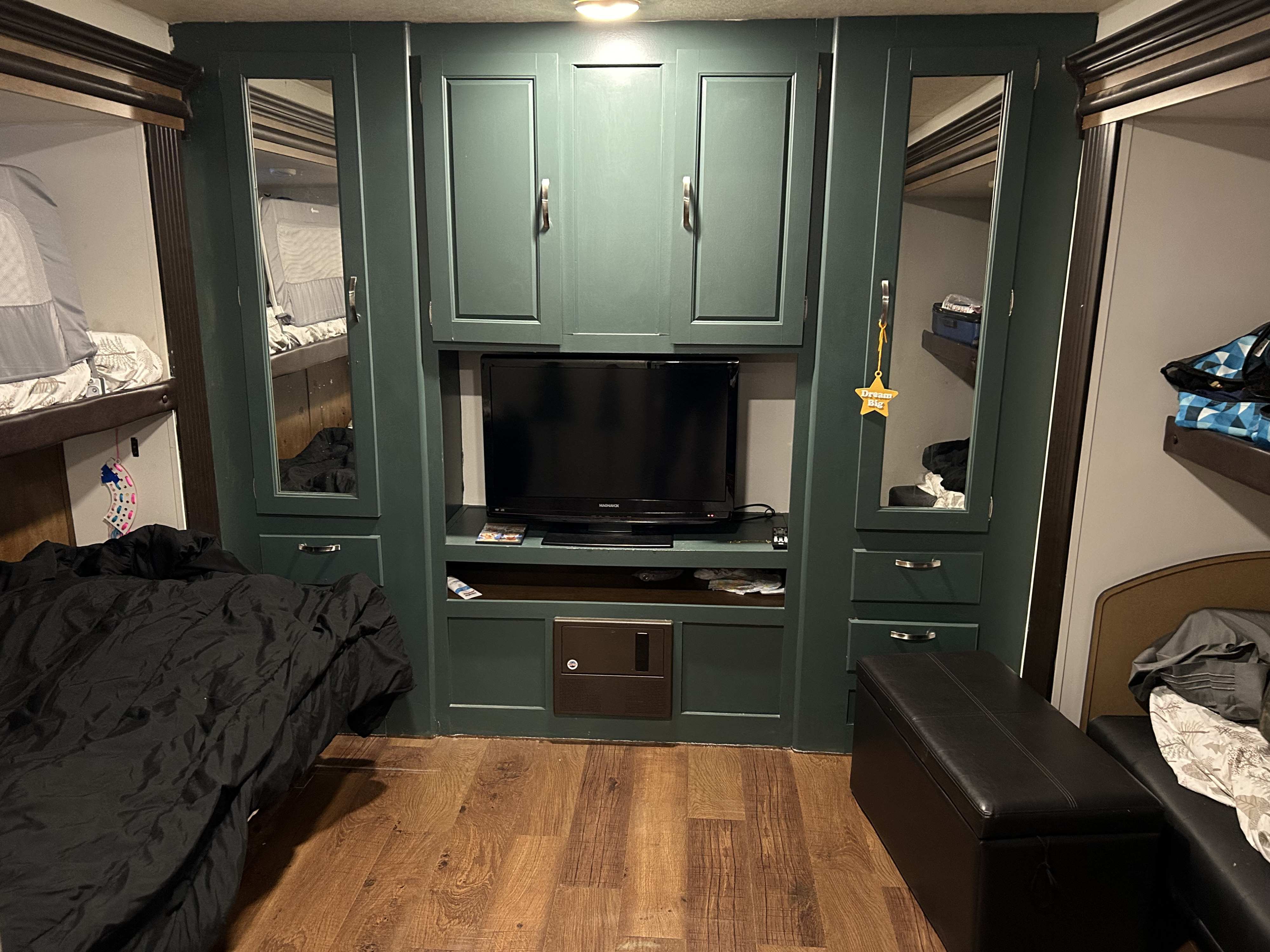 Modern RV rental bedroom. Features green storage, mirrors, TV, and bunk beds. Wood floors add warmth.. Forest River Wildwood 2018