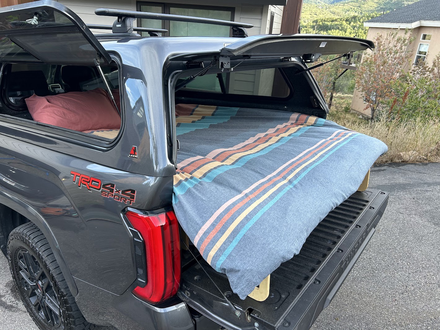 Gray truck with camper shell open, revealing a cozy bed. Perfect for rv rental, truck camping, or overland adventures.. Other Other 2024