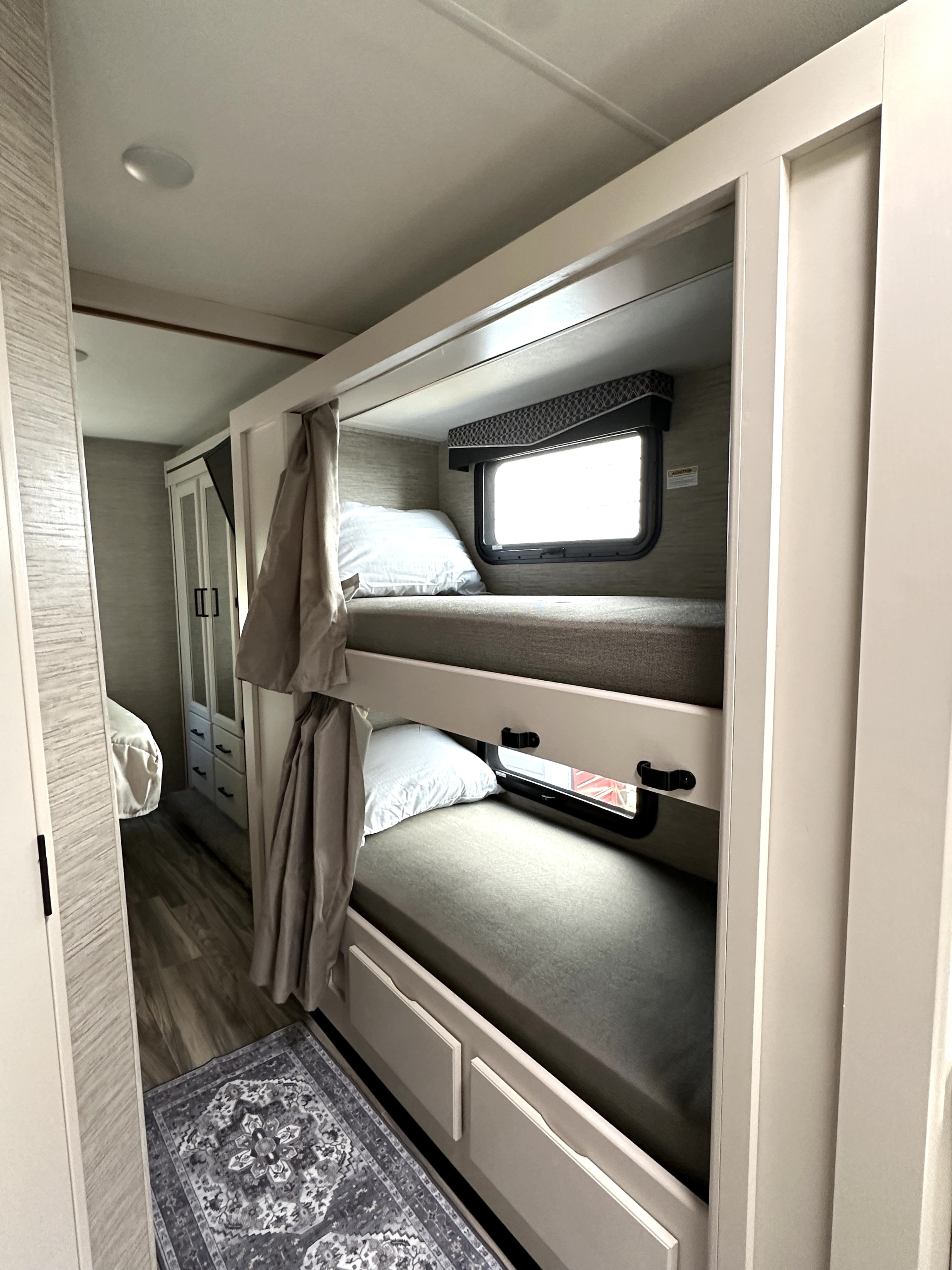 This RV rental features bright, modern bunk beds with curtains and windows, providing a comfortable sleeping area for your travels.. Thor Four Winds 2022