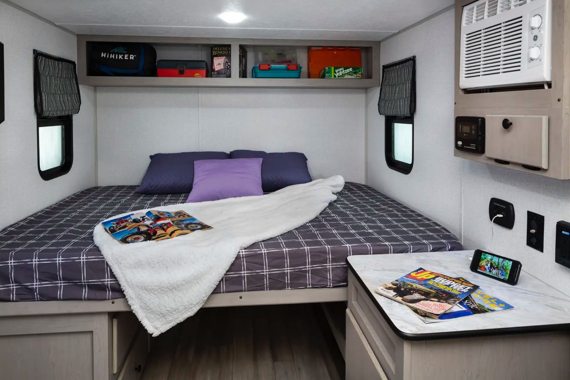 Cozy bedroom with smart storage, heat, AC, and functional nightstand with charging station. . Forest River Viking 12000 2024