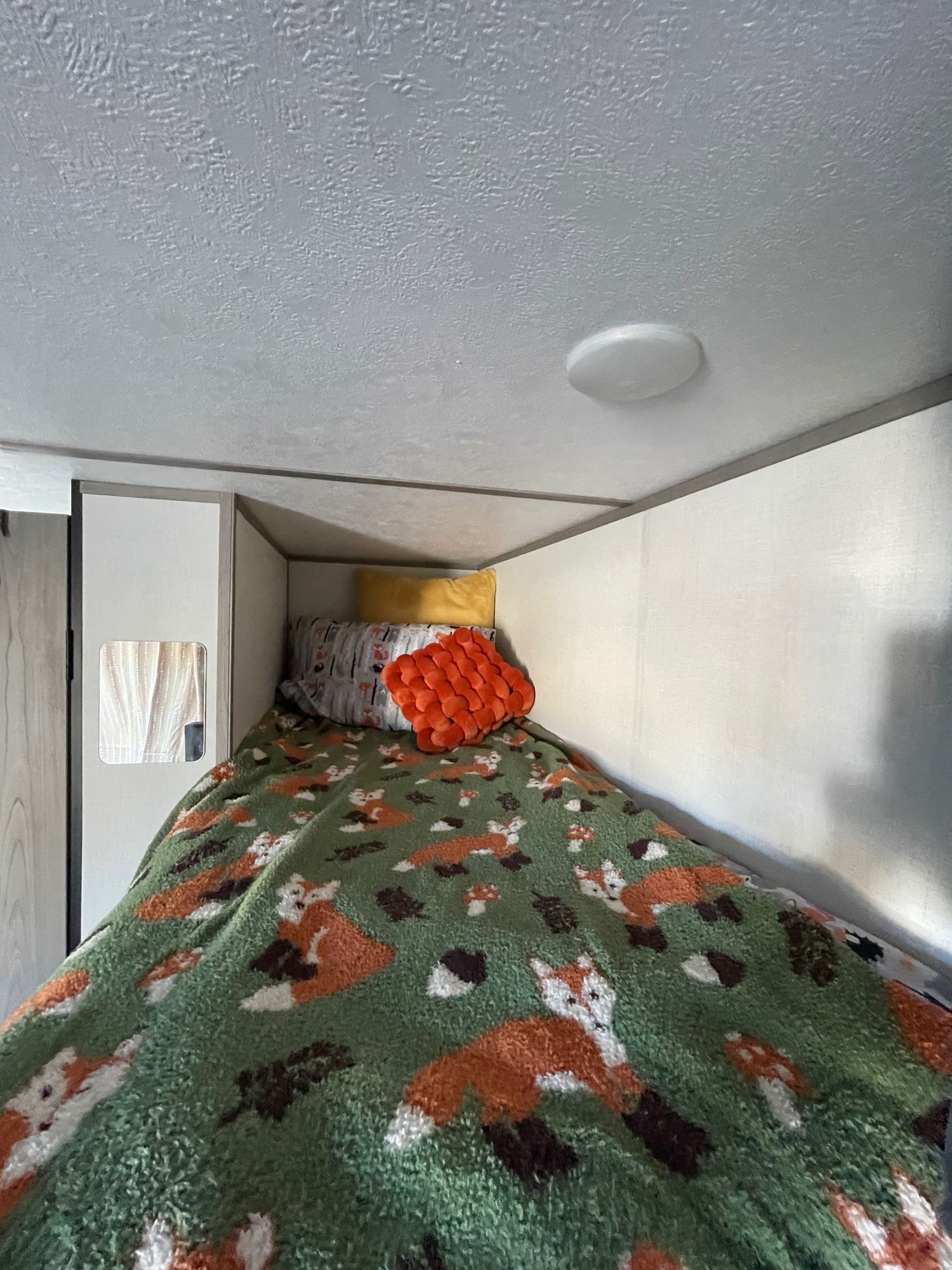 Cozy RV rental bunk bed with fox blanket and textured ceiling.. Keystone RV COLEMAN LANTERN LT 17B 2024