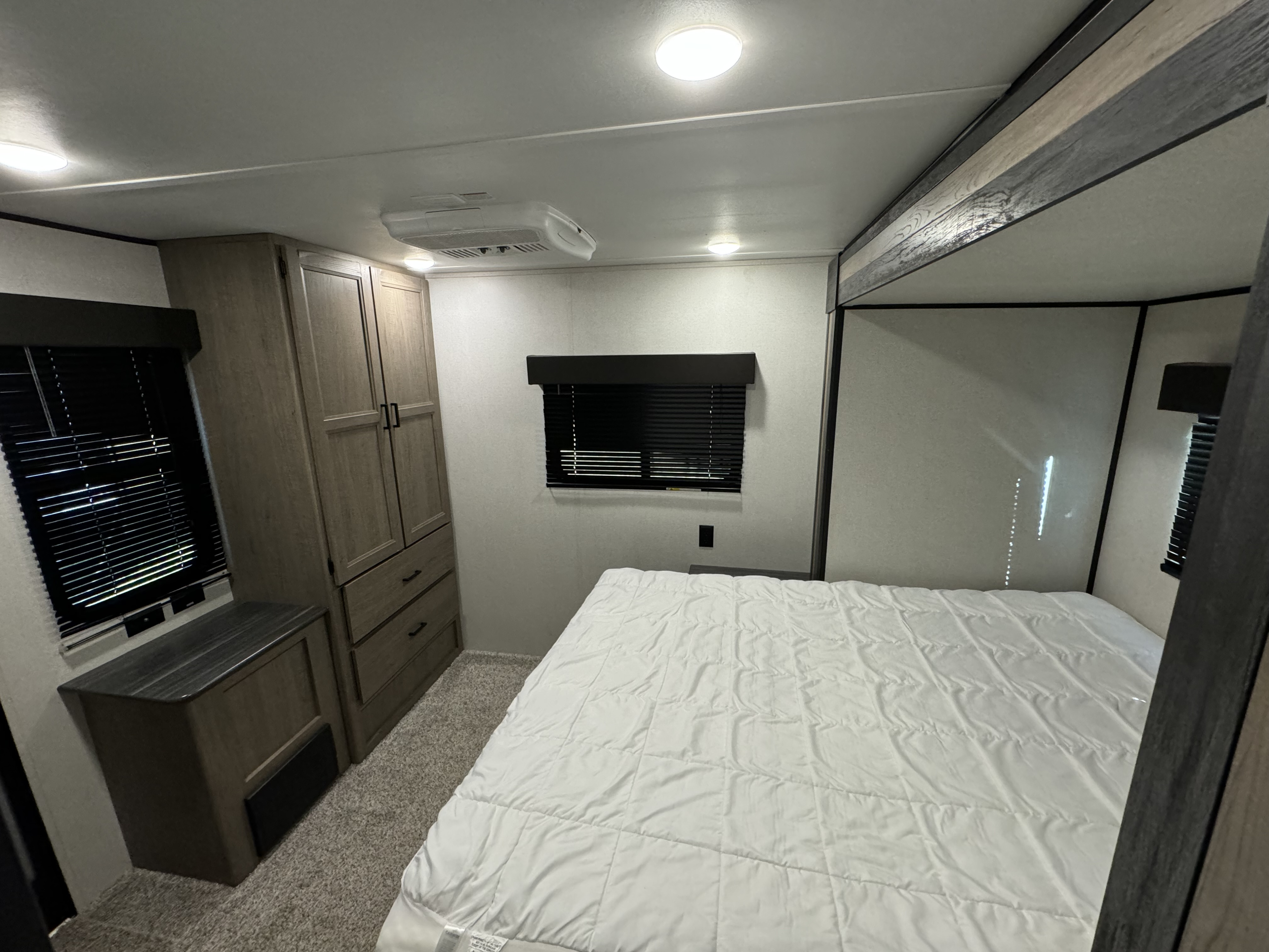 Discover this inviting RV rental bedroom. It features a comfortable bed, built-in storage, and an overhead AC unit for your travels.. Keystone Hideout 2021