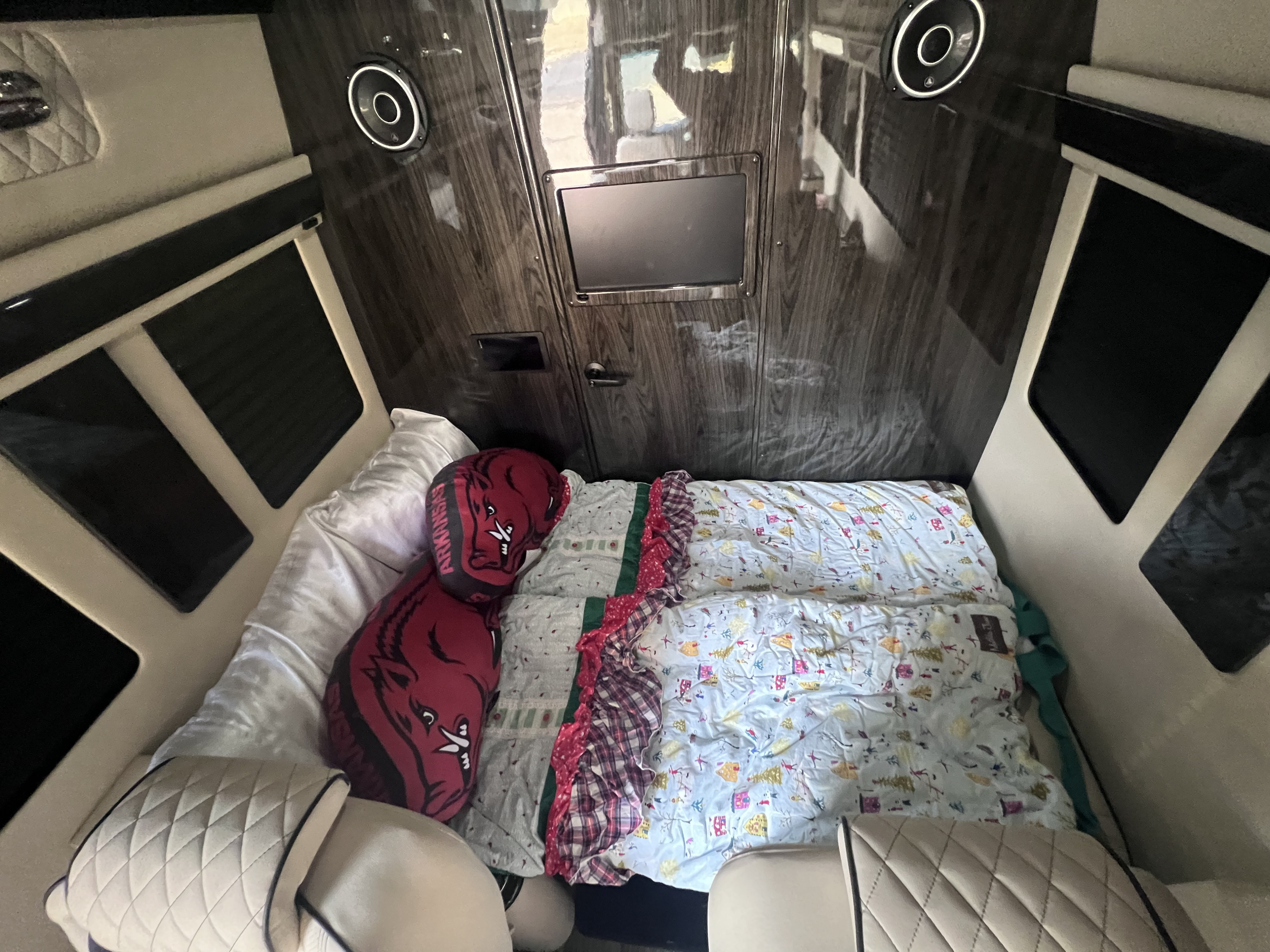 Inside a comfy RV rental: a ready bed, entertainment screen, and speakers for relaxing travels.. Ultimate Toys Ultimate Coach 2025