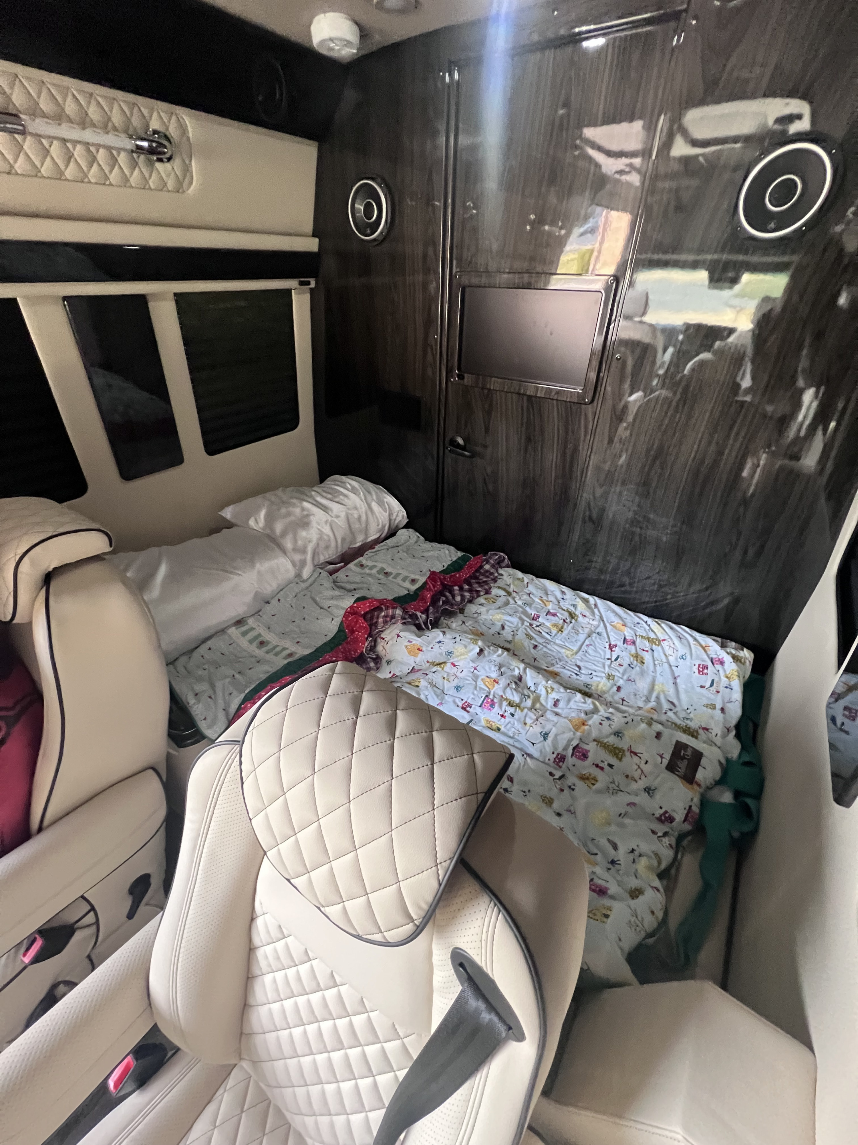 Inside a luxurious RV rental featuring a comfortable bed, quilted leather seats, and wood paneling.. Ultimate Toys Ultimate Coach 2025