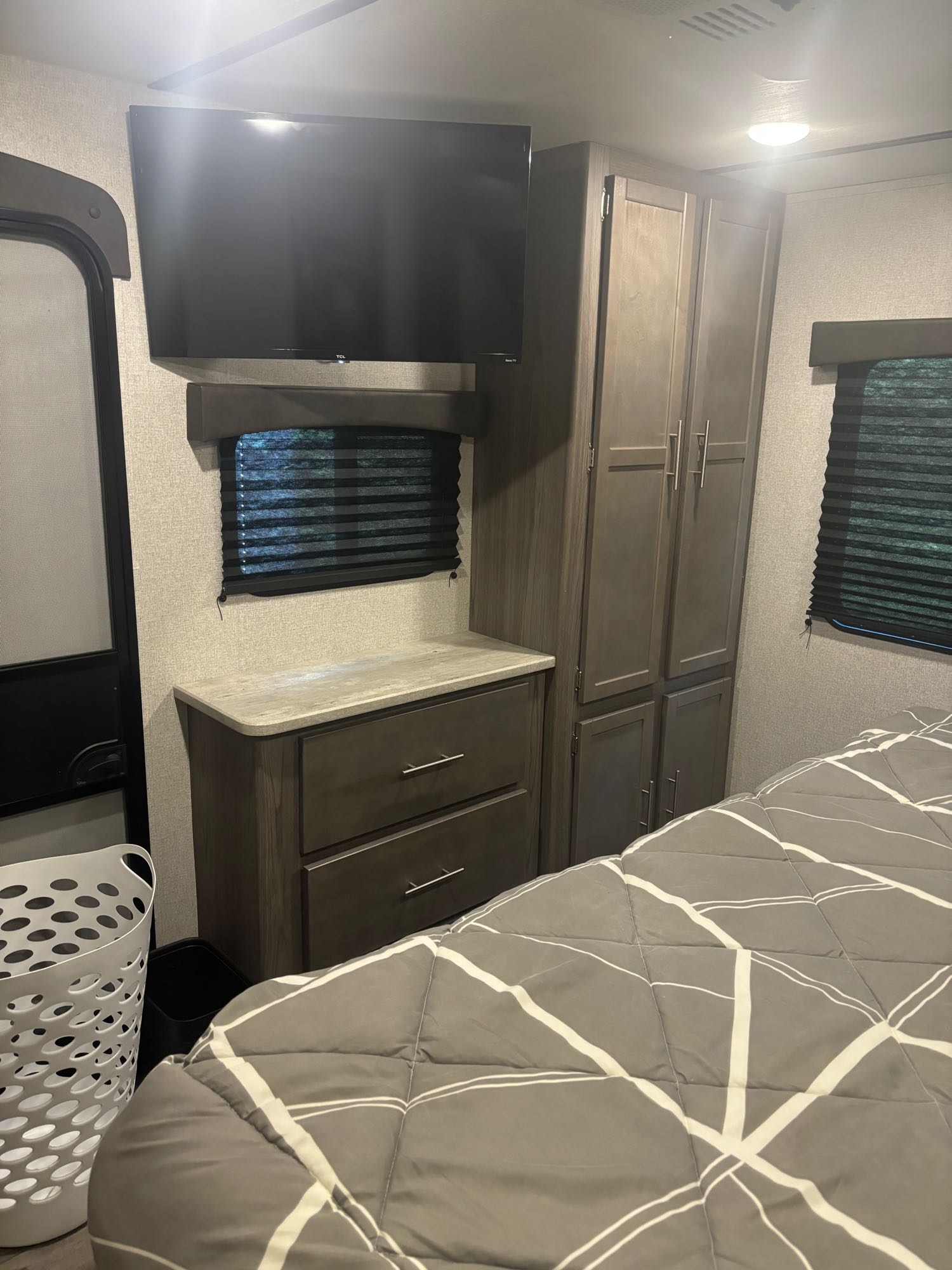 This RV rental bedroom features a mounted TV, dresser, wardrobe, and comfortable bed with modern decor.. Crossroads RV Volante 2022